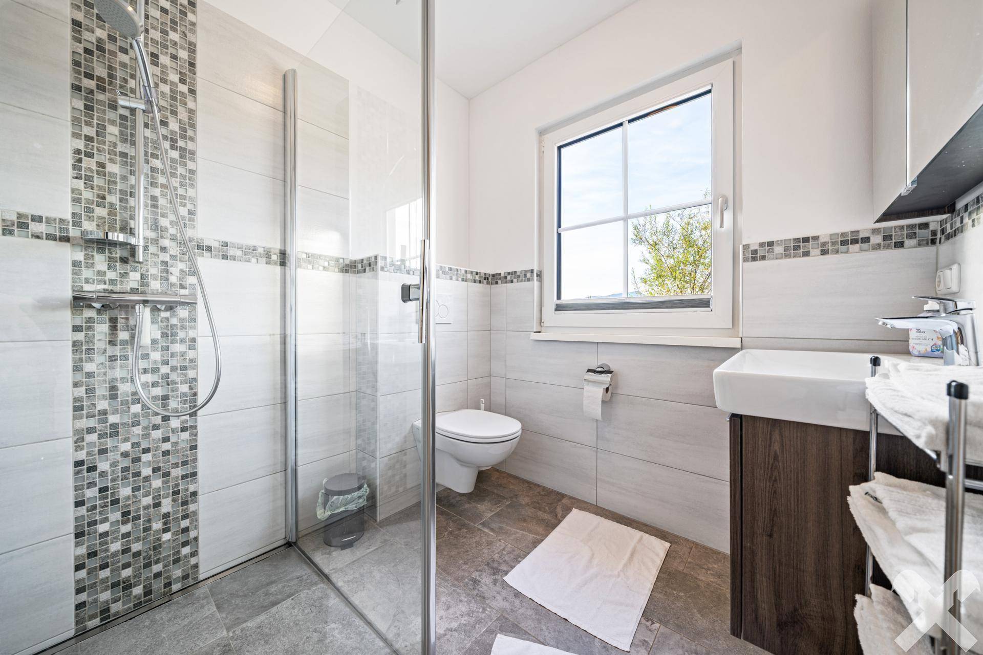 Modernes Badezimmer mit ebenerdiger Dusche, Fenster und hellen Fliesen, sehr gepflegt.