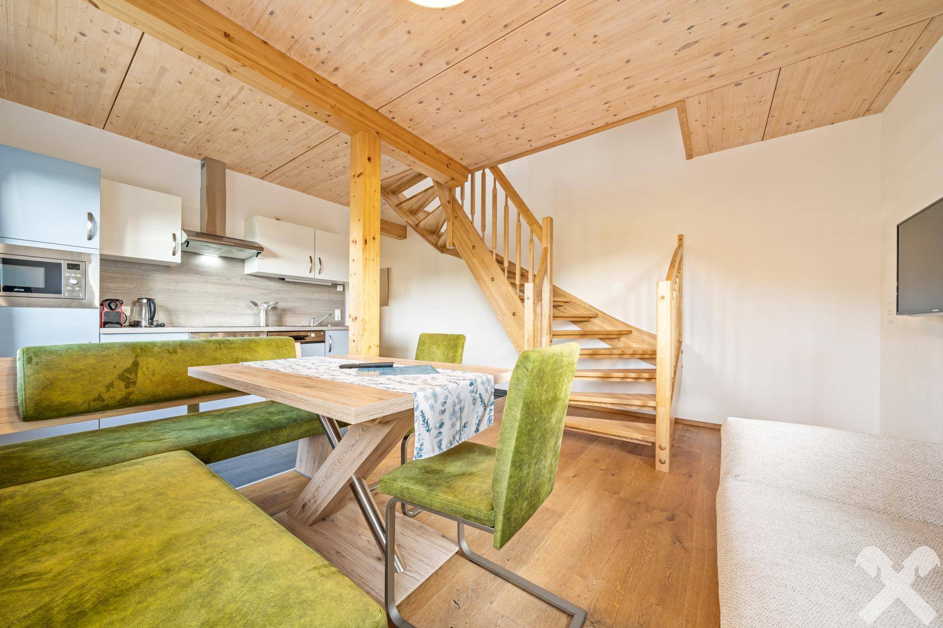 Gemütlicher Wohn-Essbereich mit Holzbalkendecke, Esstisch und Treppe zum Obergeschoss.