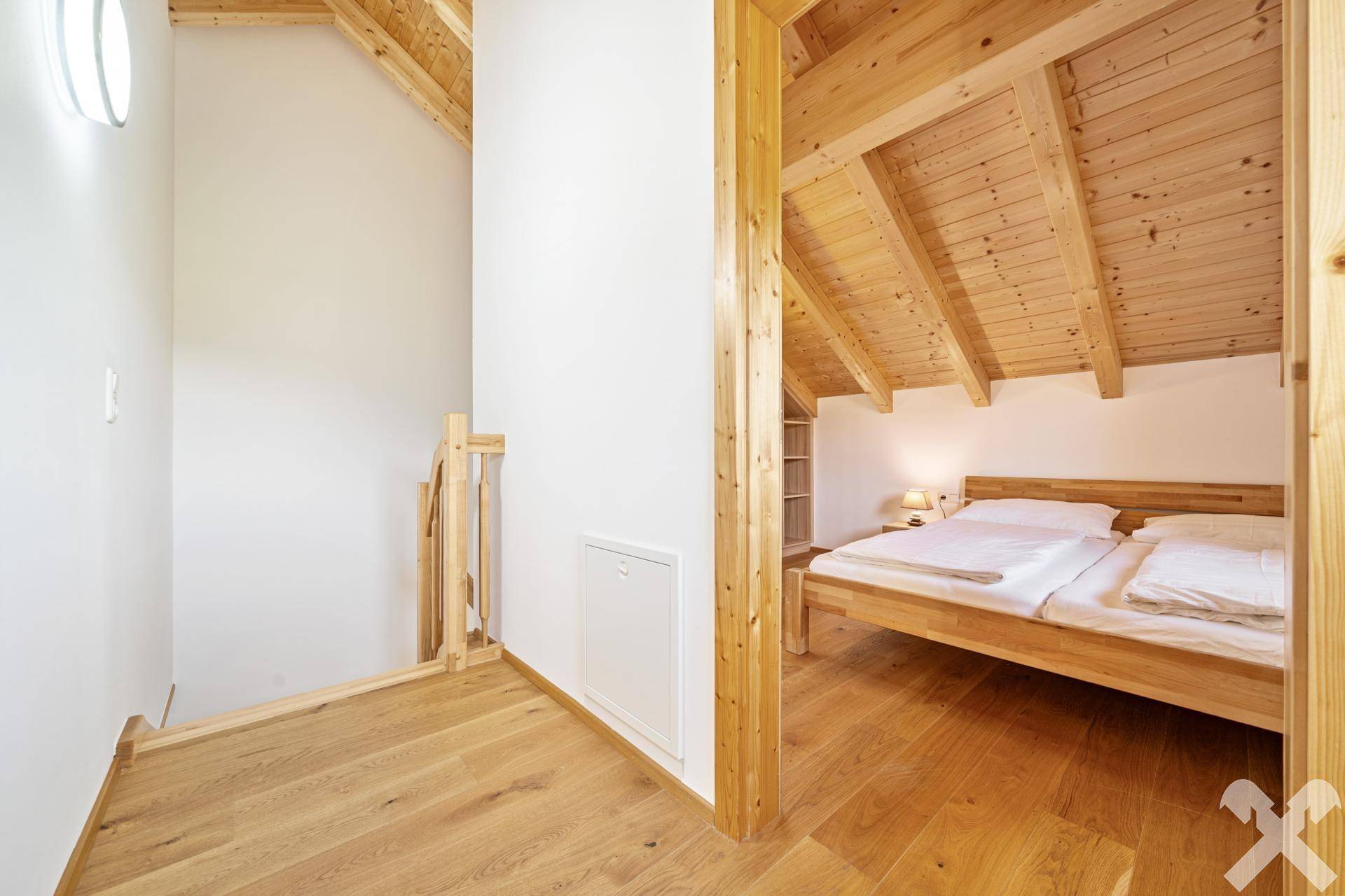 Heller Flur im Obergeschoss mit Holzboden und Zugang zu einem gemütlichen Schlafzimmer.