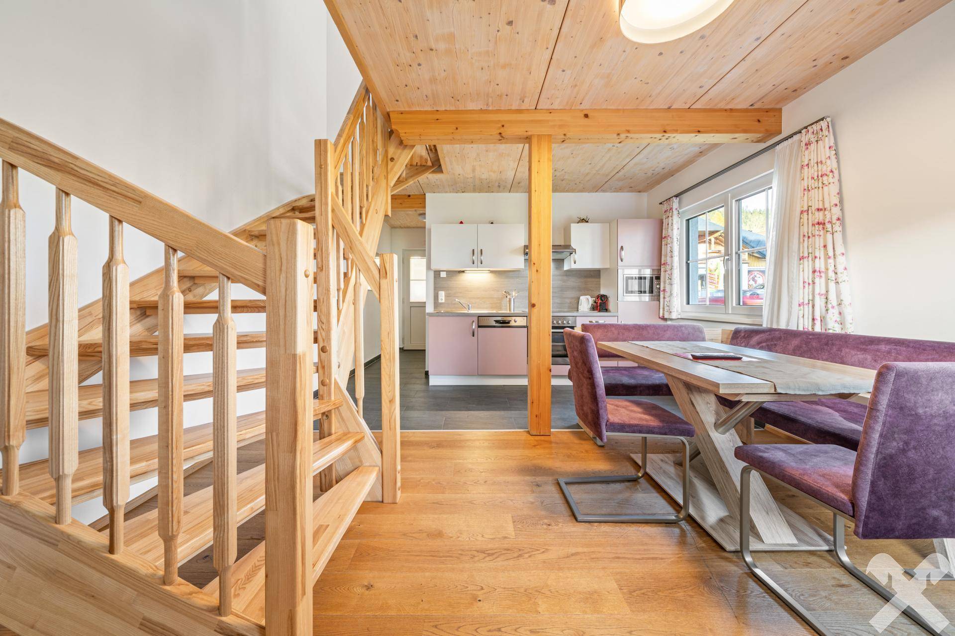 Gemütlicher Wohn-Essbereich mit Holzbalkendecke, Esstisch und Treppe zum Obergeschoss.