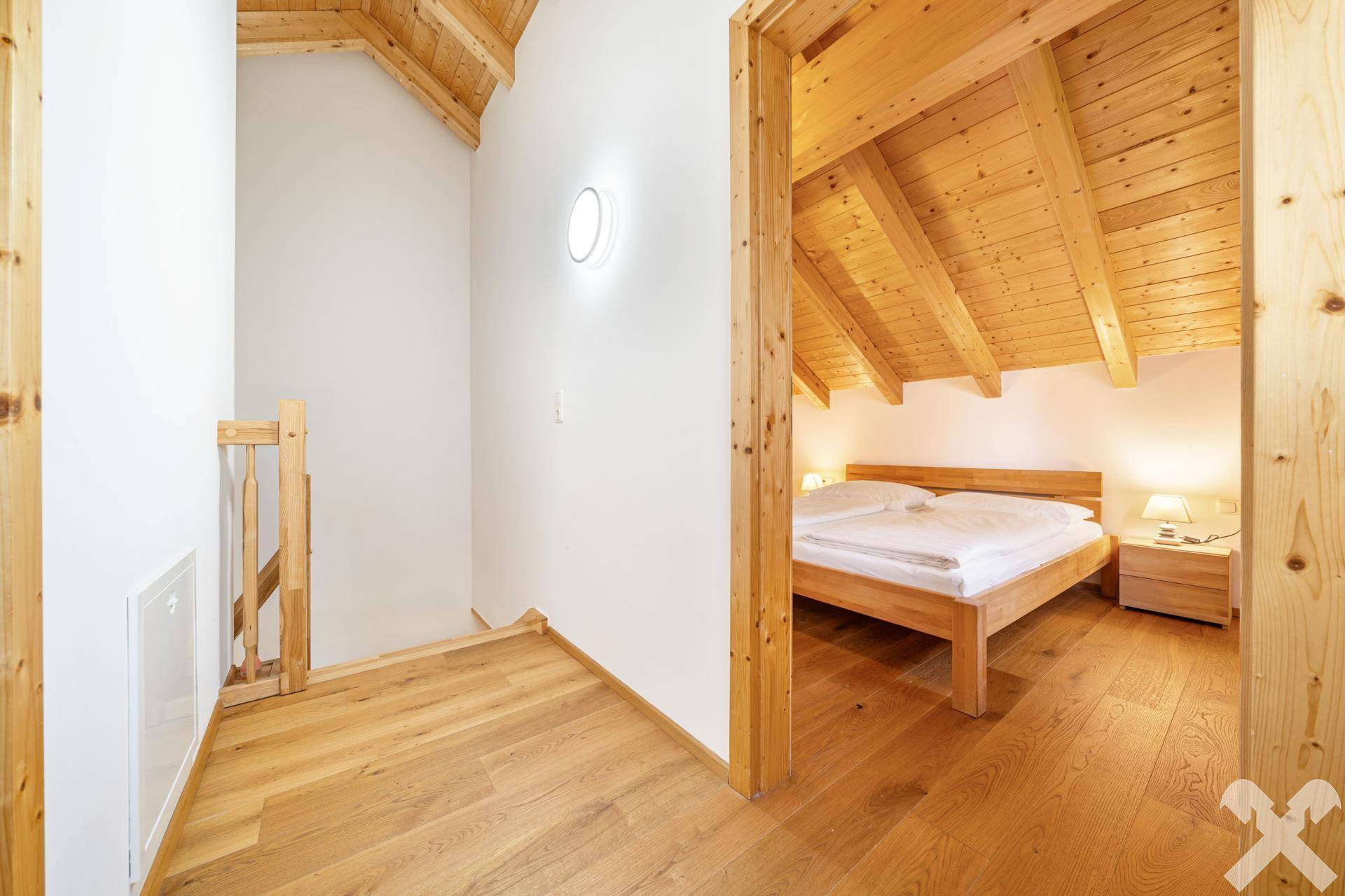 Heller Flur im Obergeschoss mit Holzboden und Zugang zu einem gemütlichen Schlafzimmer.