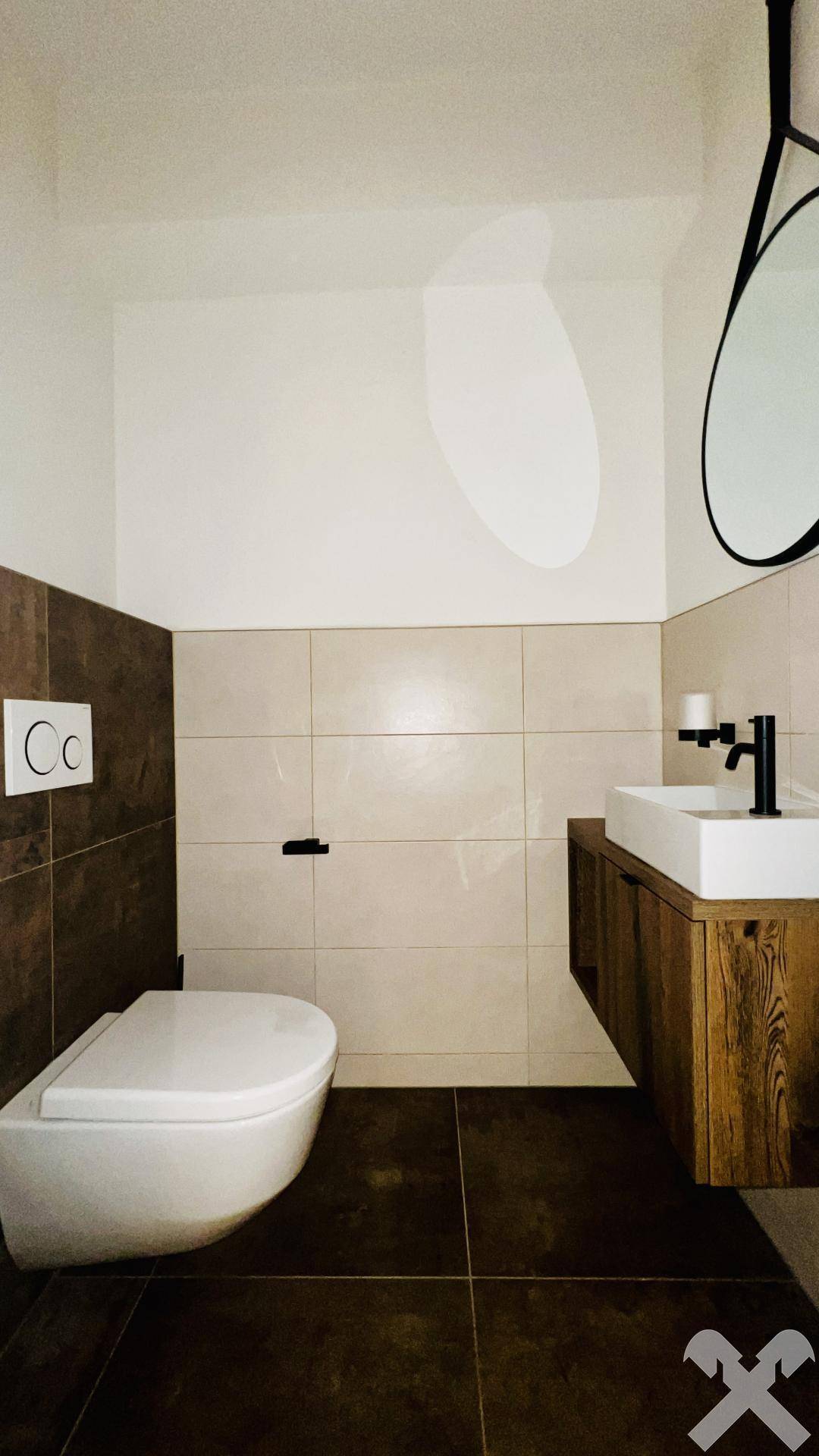 Modernes Gäste-WC mit Wand-WC, Waschbecken und dunklen Bodenfliesen.