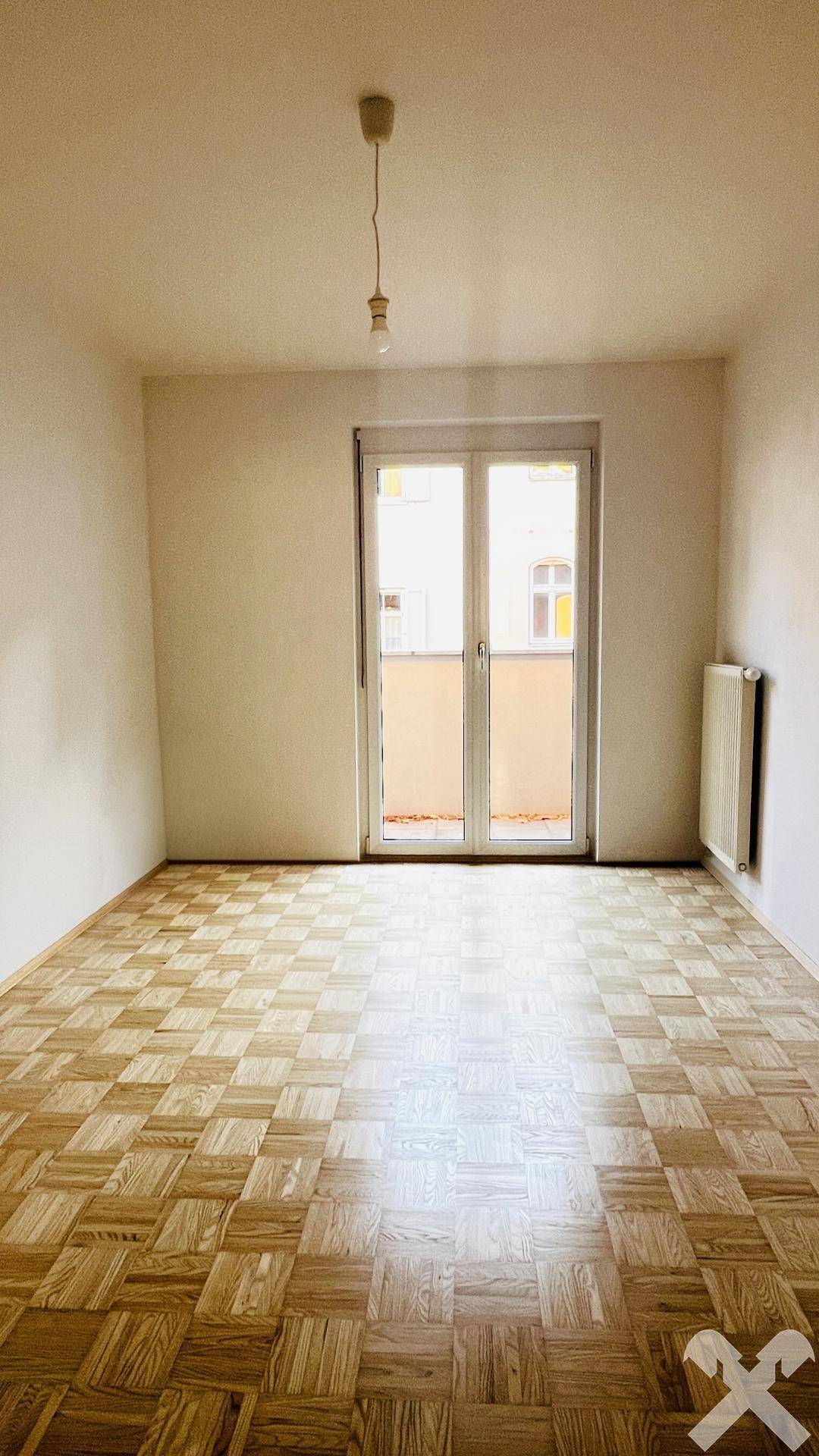 Geräumiges Zimmer mit Parkettboden und großem Fenster für viel Tageslicht.