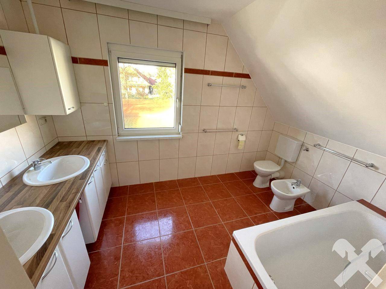 Geräumiges Badezimmer im Dachgeschoss mit Badewanne, Bidet, Doppelwaschbecken und Fenster.