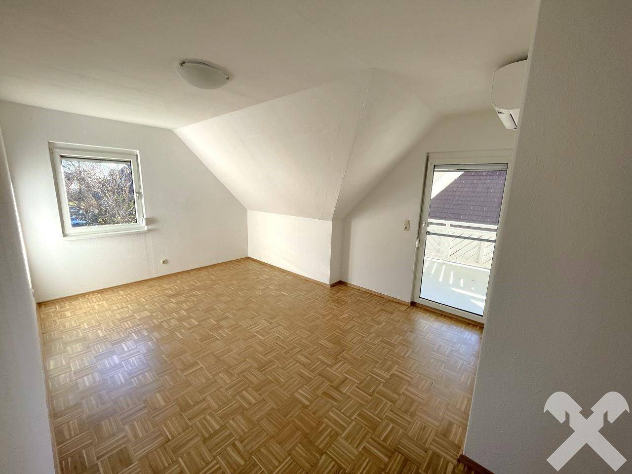 Gemütliches Schlafzimmer im Dachgeschoss mit Parkettboden, Fenster und Balkonzugang.