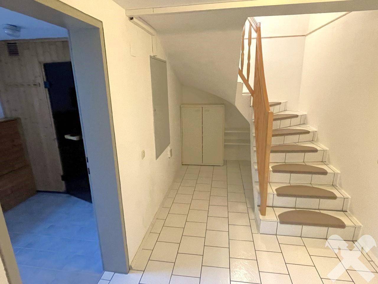 Kellerflur mit Treppe und Zugang zum Wellnessbereich mit Sauna.