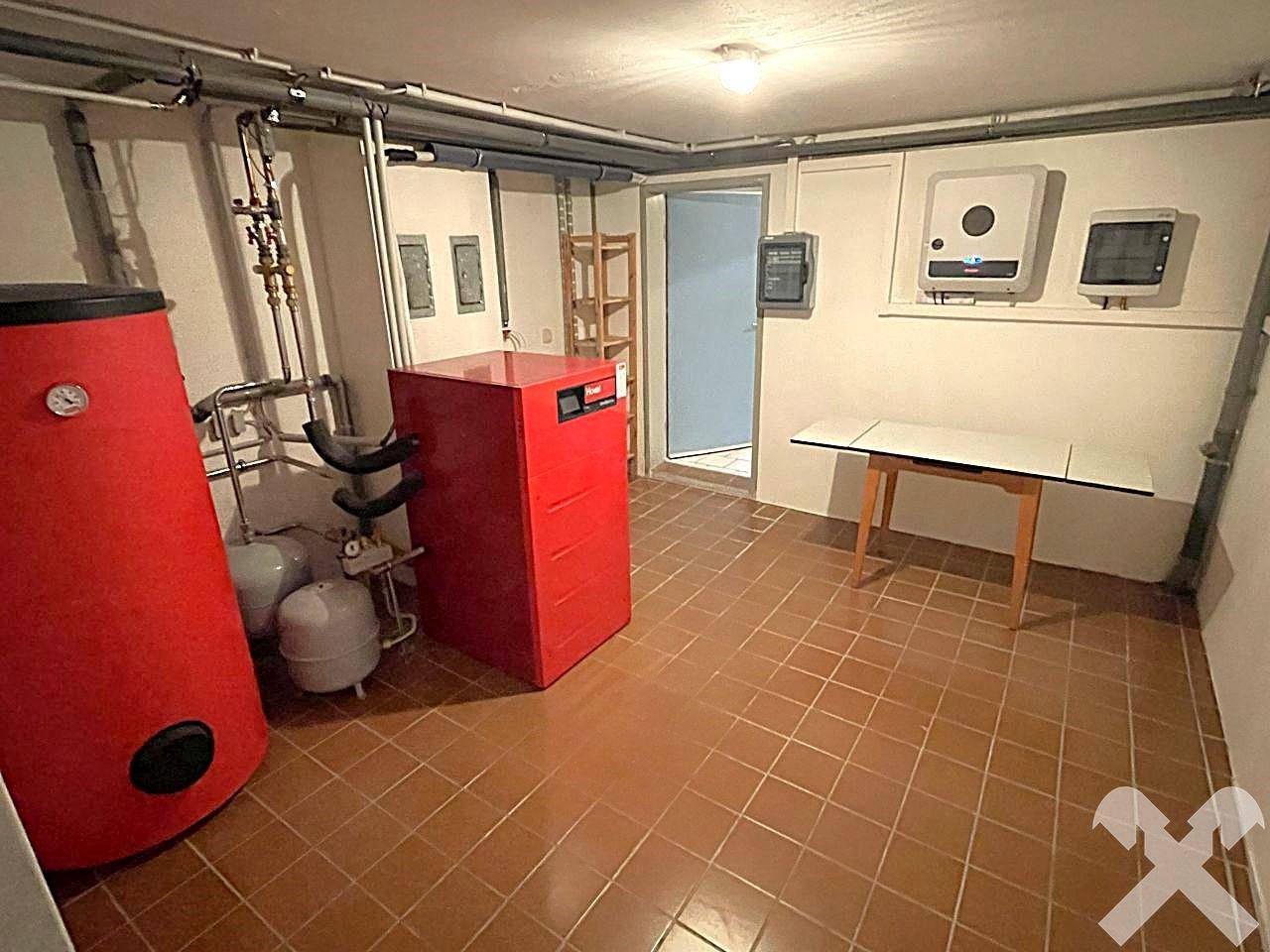Heizungsraum im Keller mit modernen Anlagen und Fliesenboden.