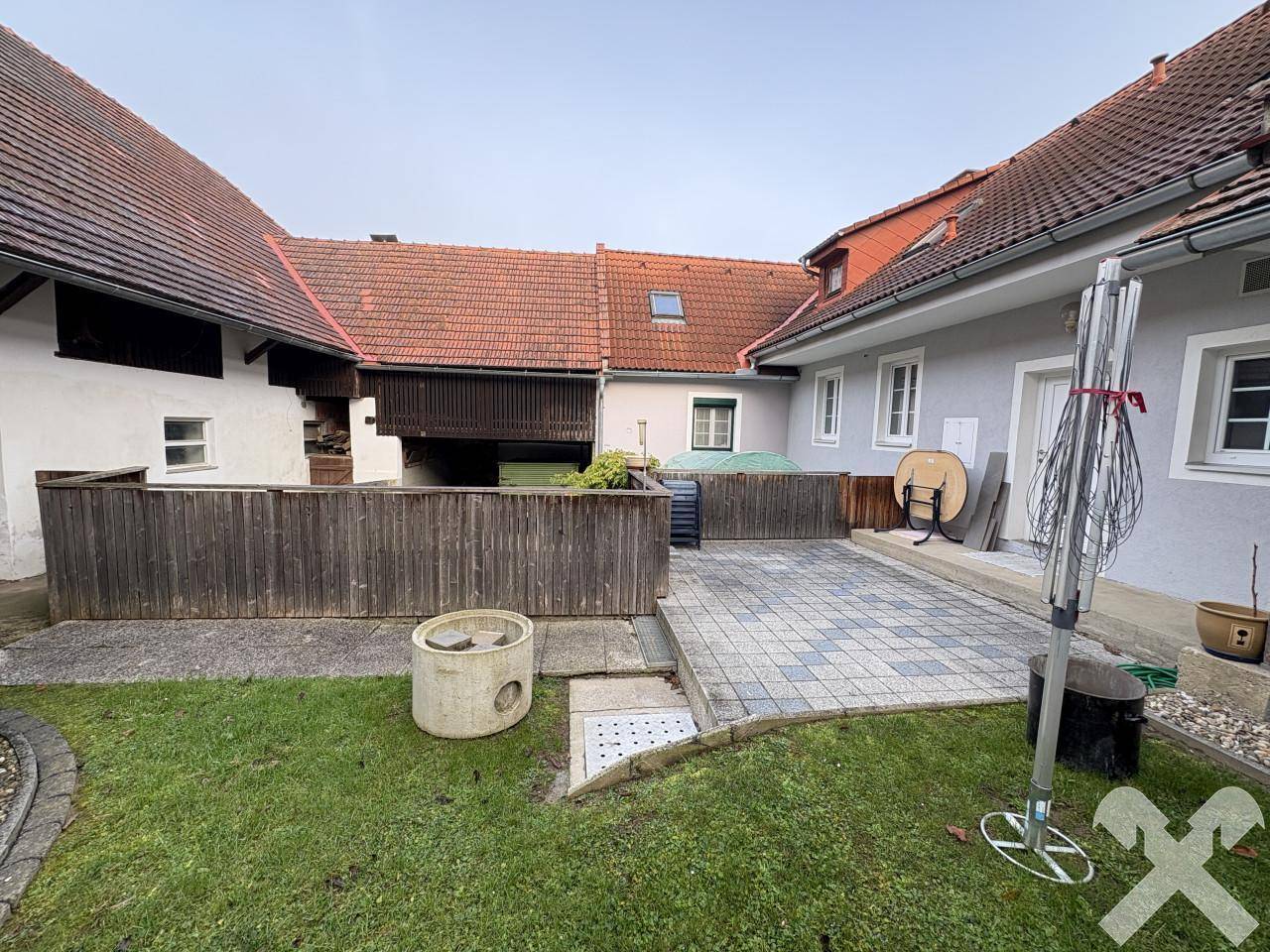 Innenhof mit Rasenfläche, gepflastertem Sitzbereich und Blick auf die umliegenden Wirtschaftsgebäude.