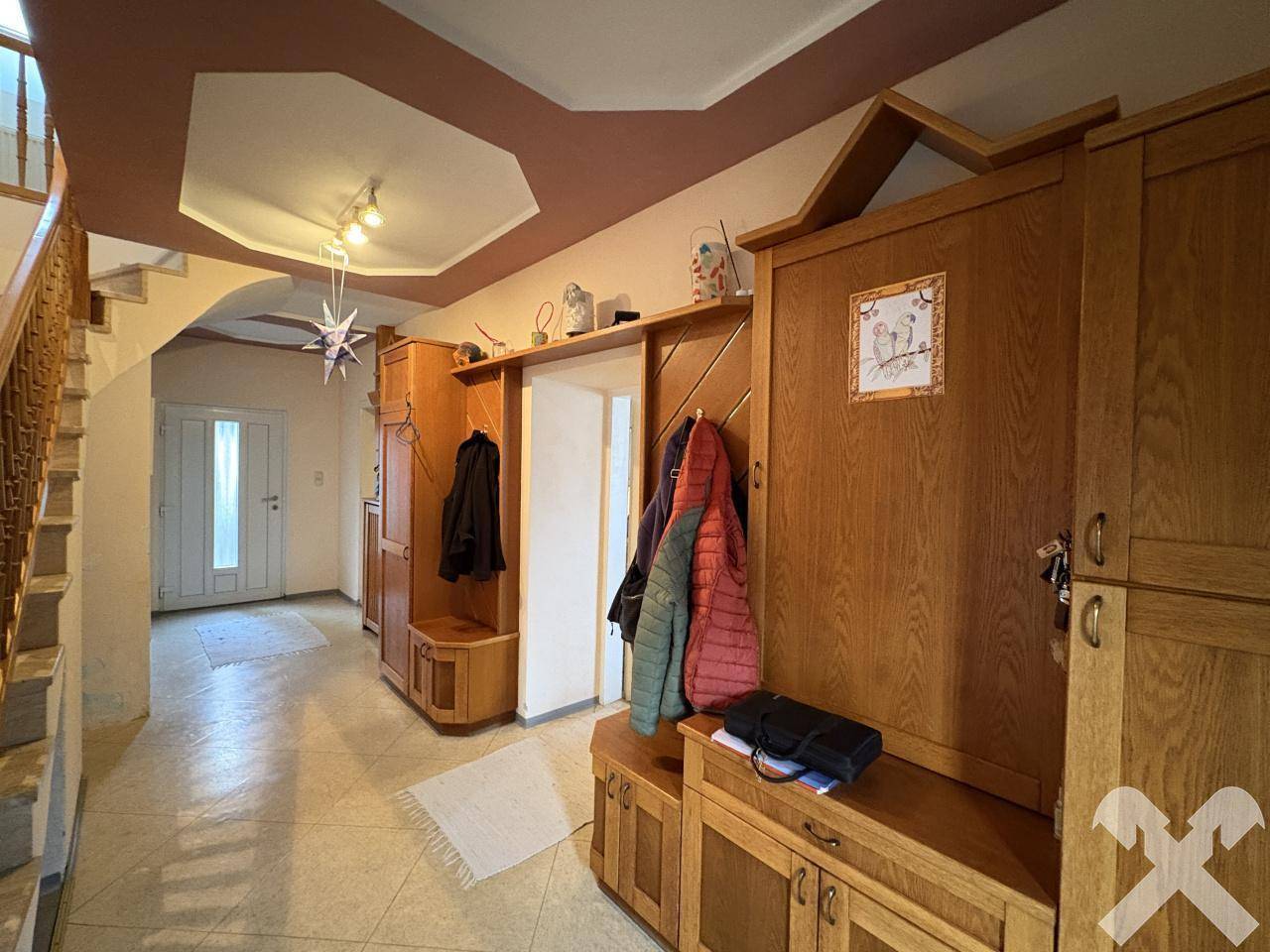 Geräumiger Eingangsbereich mit Holzmöbeln, Garderobe und Treppe zum Obergeschoss.
