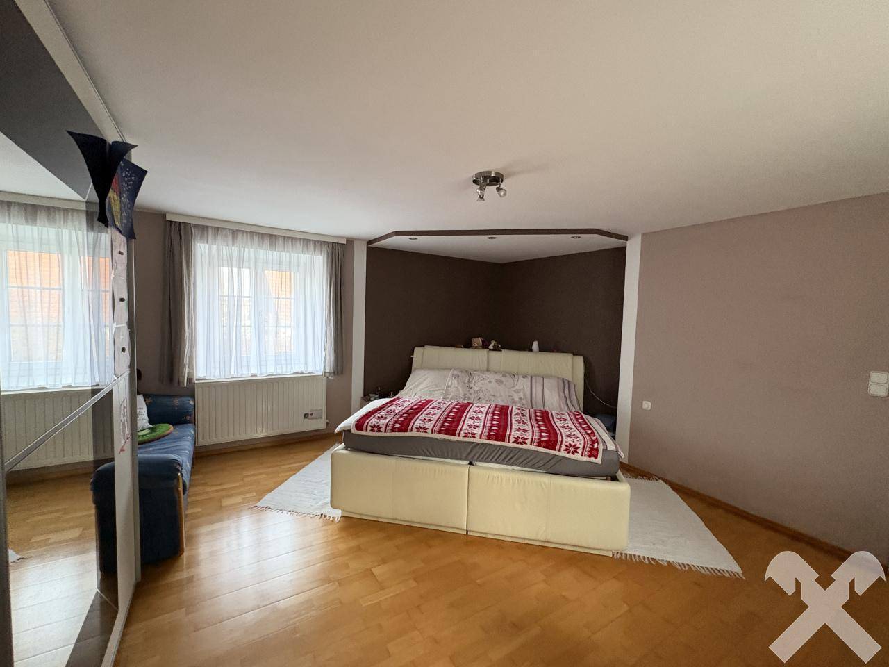 Helles Schlafzimmer mit großem Doppelbett, braunen Wänden und Parkettboden.