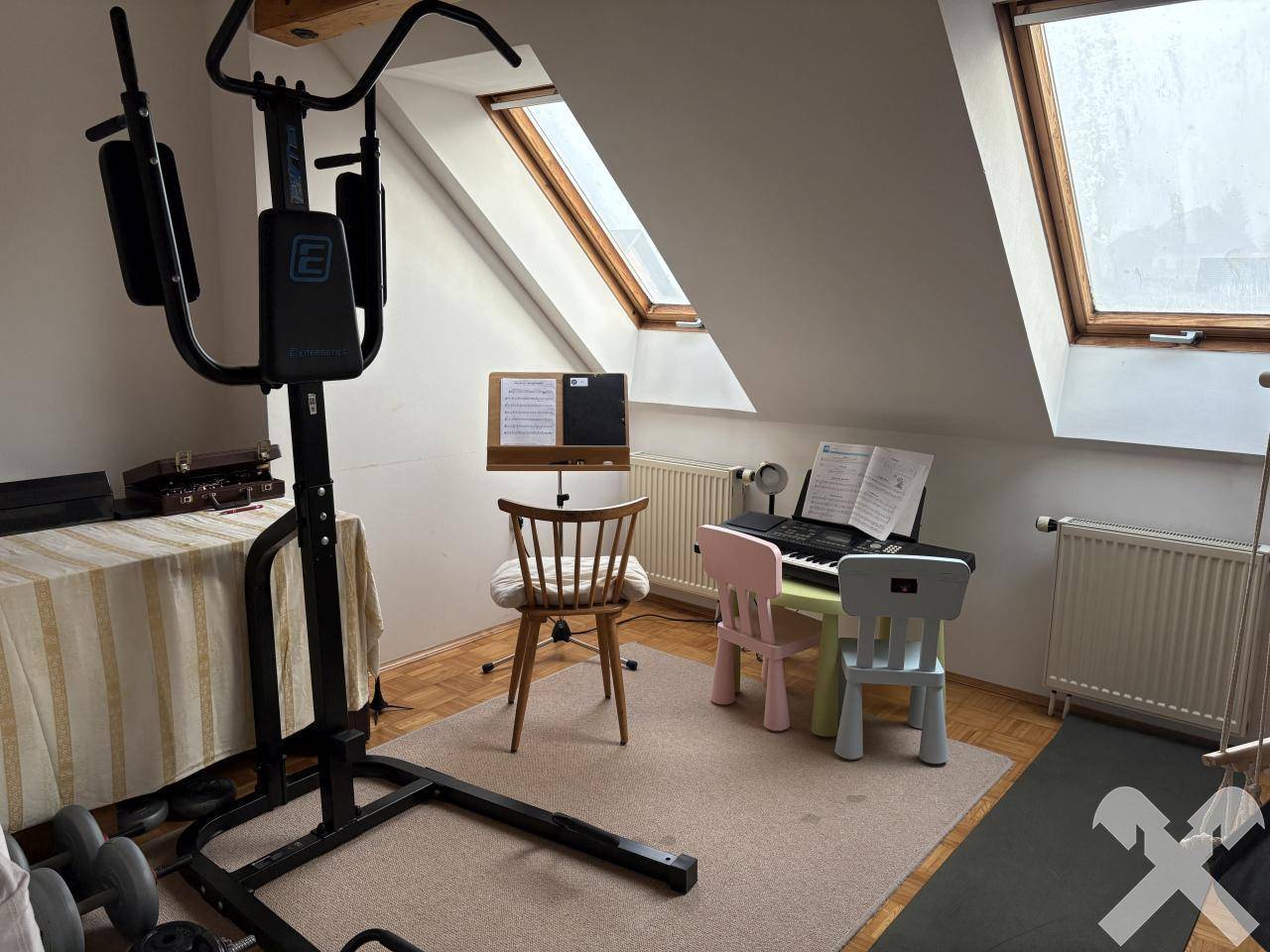 Dachgeschosszimmer mit Dachfenstern, Sportgeräten und einem kleinen Musikbereich.