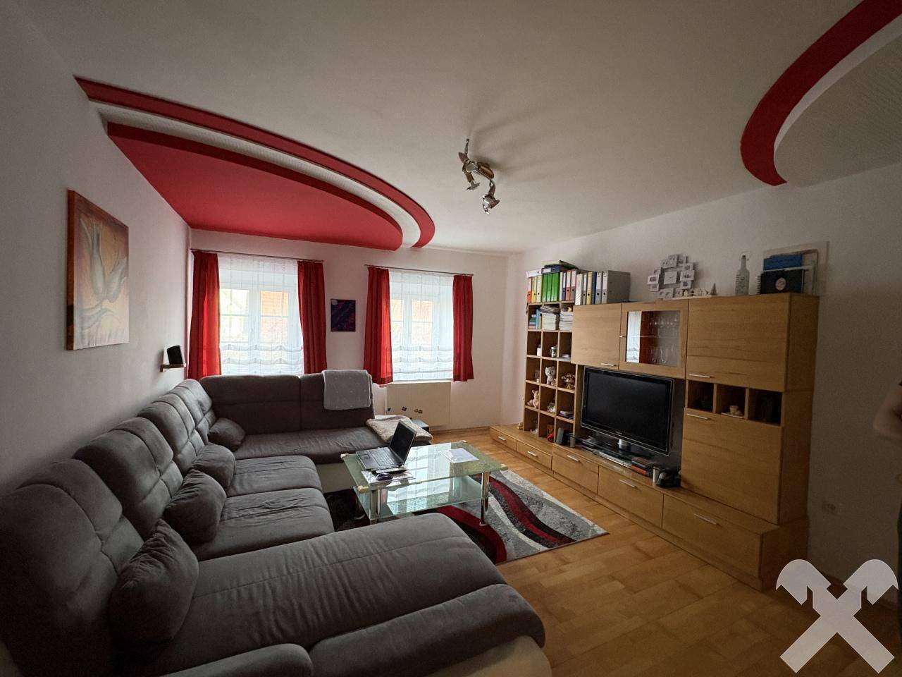 Modernes Wohnzimmer mit großer Eckcouch, Holzmöbeln und einer auffälligen Deckenbeleuchtung.
