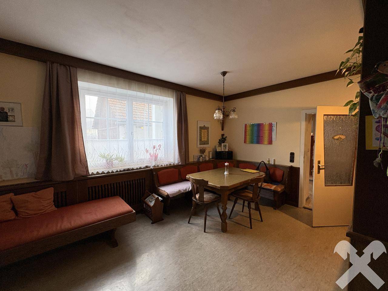 Gemütlicher Essbereich mit Holztisch, Eckbank und Blick durch das Fenster ins Grüne.