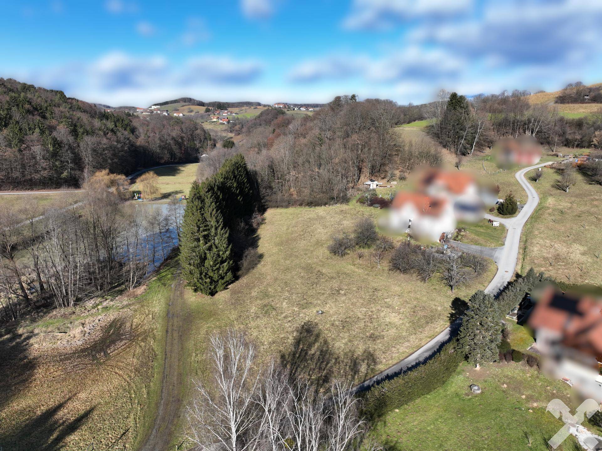Panoramische Luftaufnahme eines großen Grundstücks mit Wiesen, Wald und einem See, umgeben von ländlicher Idylle.