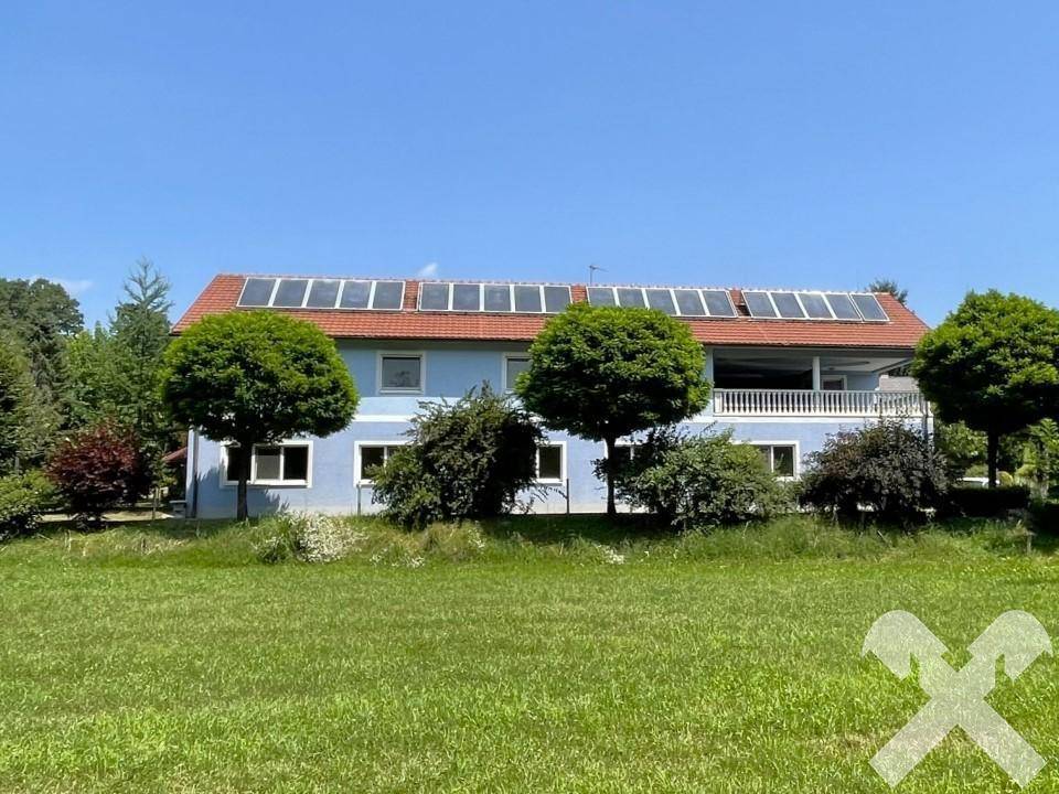 Gebäudeansicht von einem Feld aus mit Solaranlage auf dem Dach und weitem Grünblick.