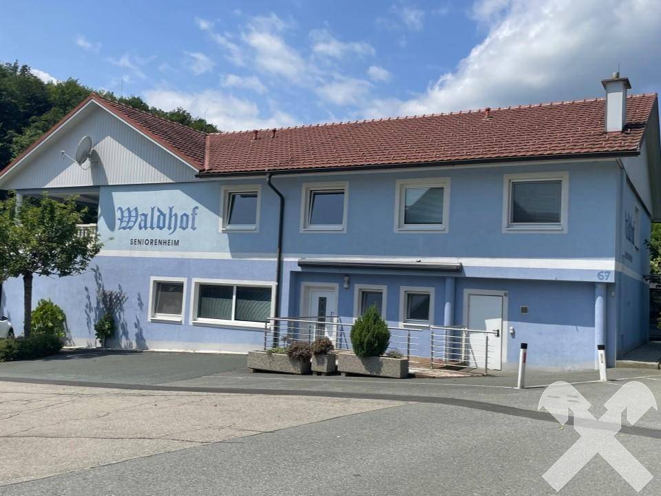 Gebäudefassade mit barrierefreier Rampe zum Eingang, blauer Außenwand und Fenstern.