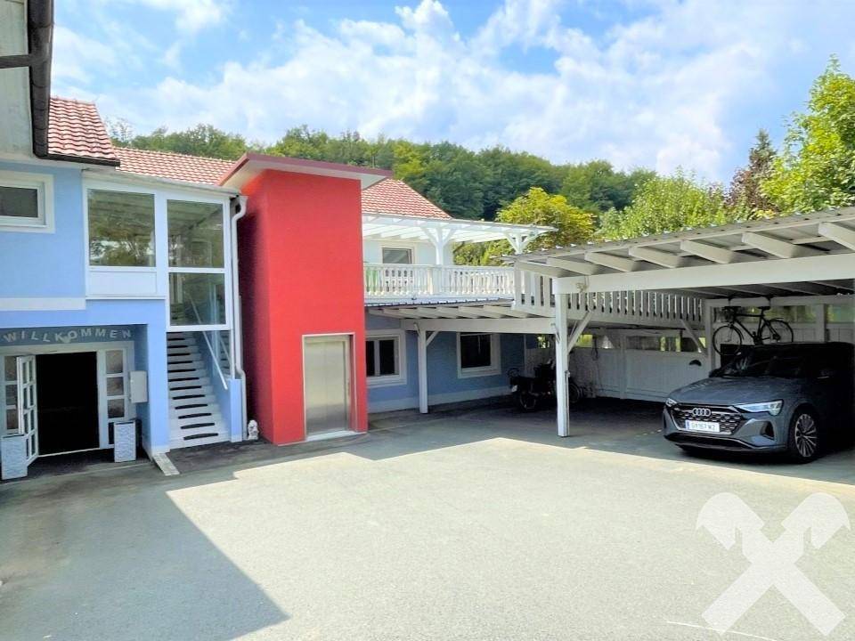 Seitenansicht des Gebäudes mit externem Aufzug, Carport und Eingangsbereich.