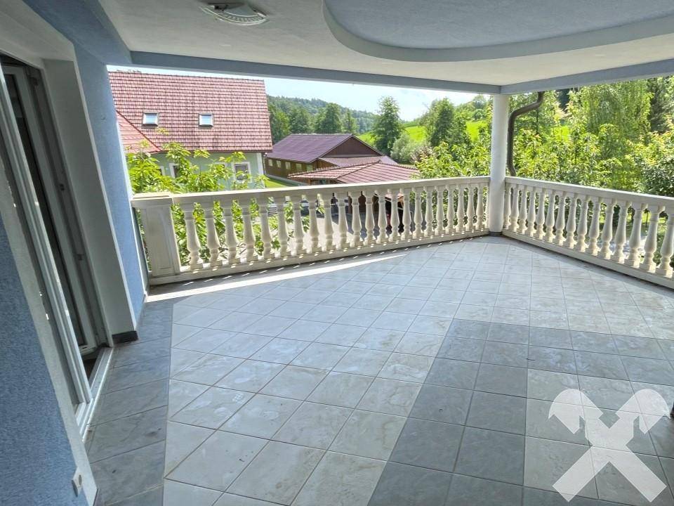 Geräumiger Balkon mit Fliesenboden, Balustrade und weitem Blick ins Grüne.