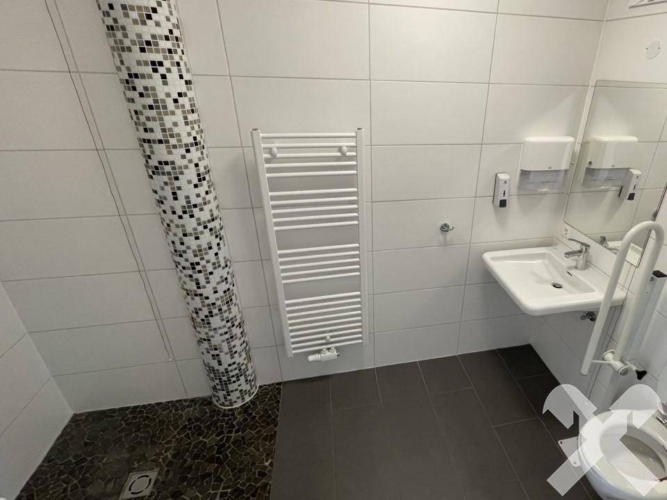 Barrierefreies Badezimmer mit ebenerdiger Dusche, Haltegriffen und beheiztem Handtuchhalter.