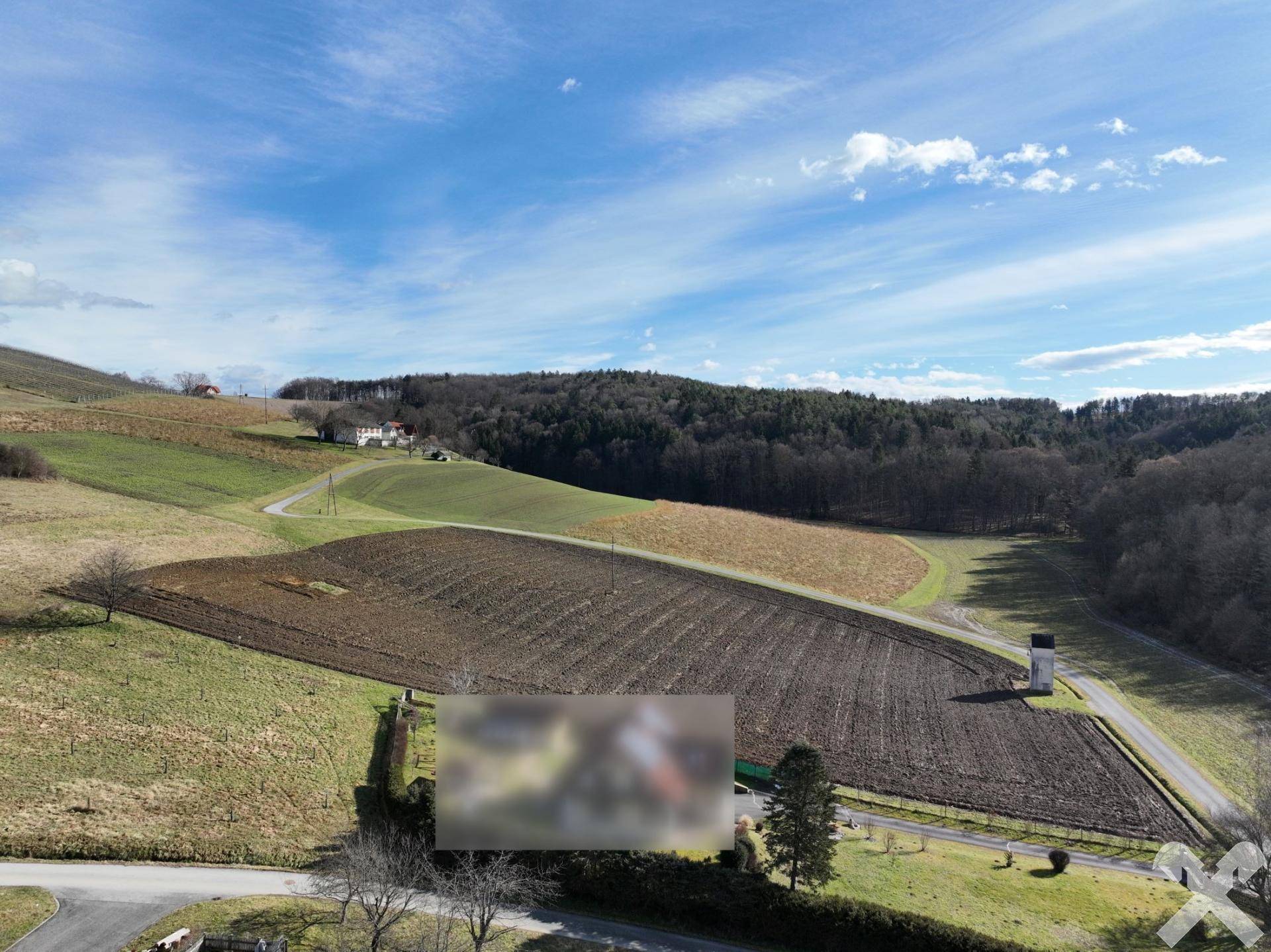 Panoramablick aus der Vogelperspektive auf weite Felder, bewaldete Hügel und eine ländliche Straße.