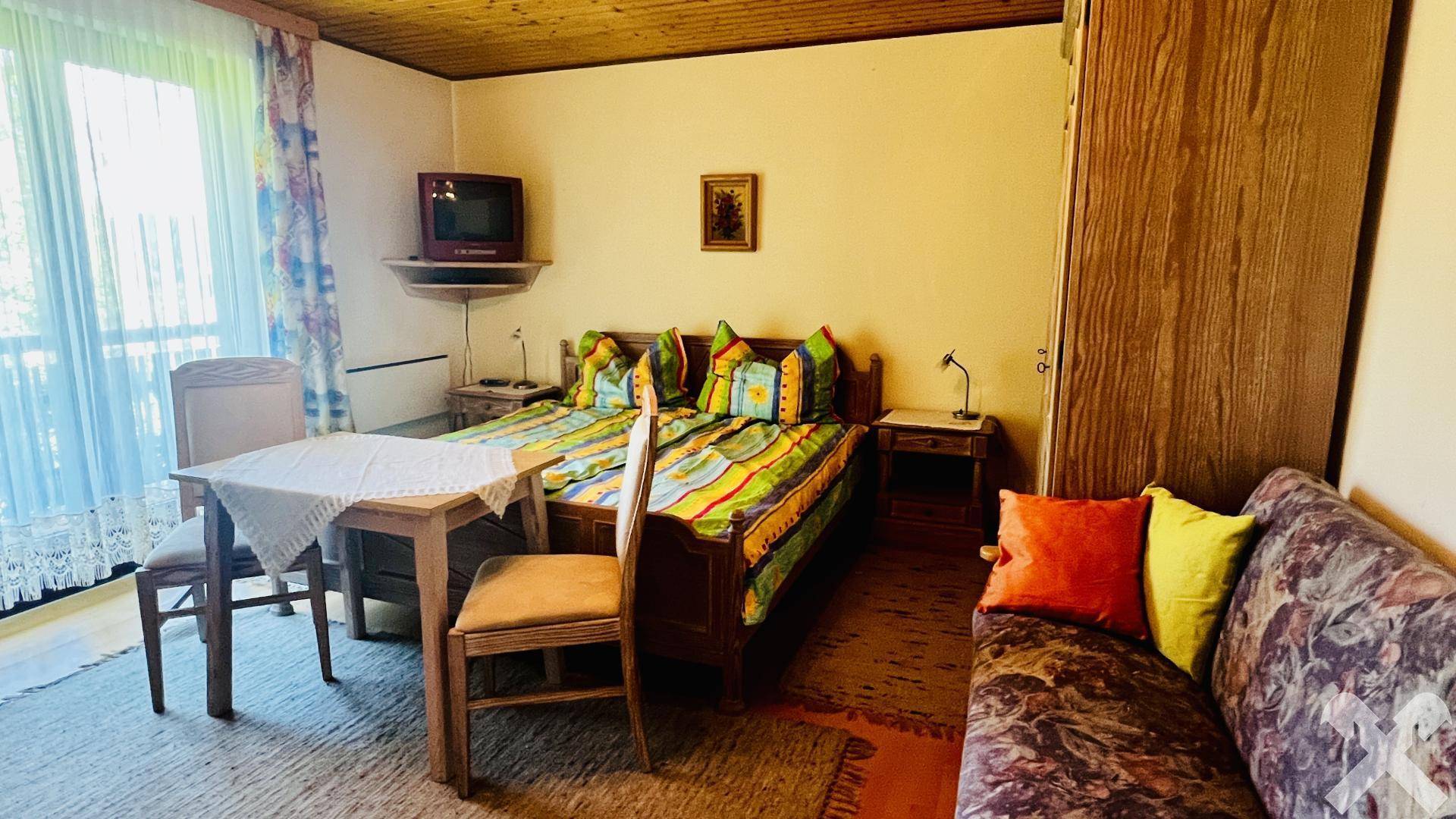 Helles Schlafzimmer mit zwei Einzelbetten, Sofa und Zugang zum Balkon.