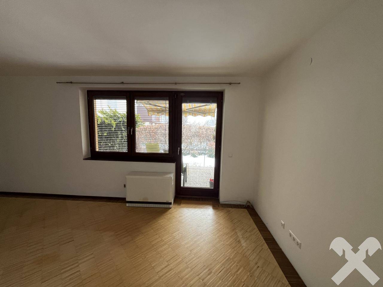 Heller Wohnbereich mit Parkettboden und Zugang zur Terrasse durch eine große Tür.