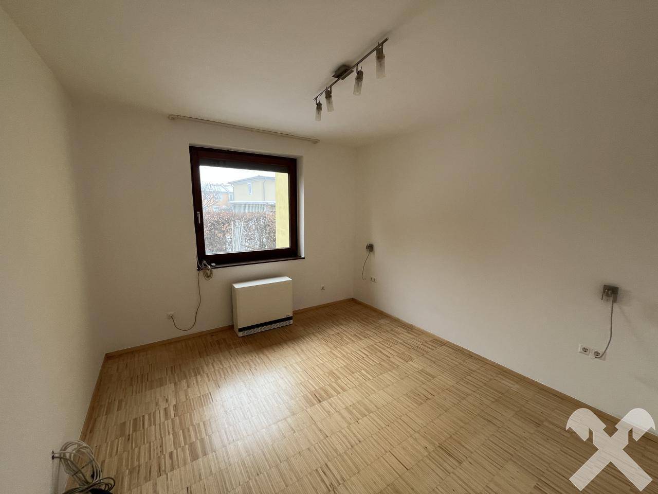 Schlafzimmer mit Parkettboden und einem Fenster, bereit zur Einrichtung.