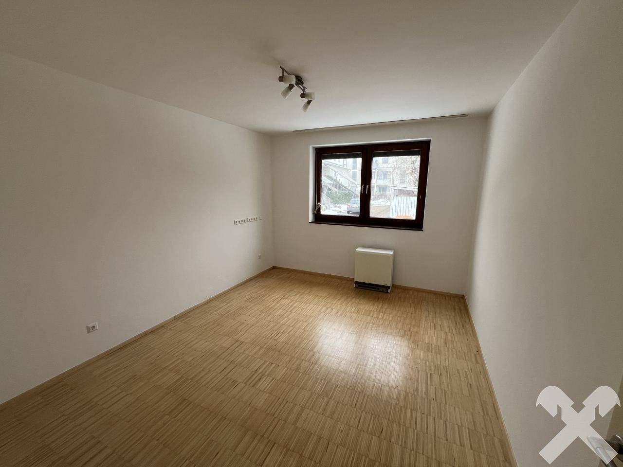 Helles Schlafzimmer mit Parkettboden und einem Fenster.