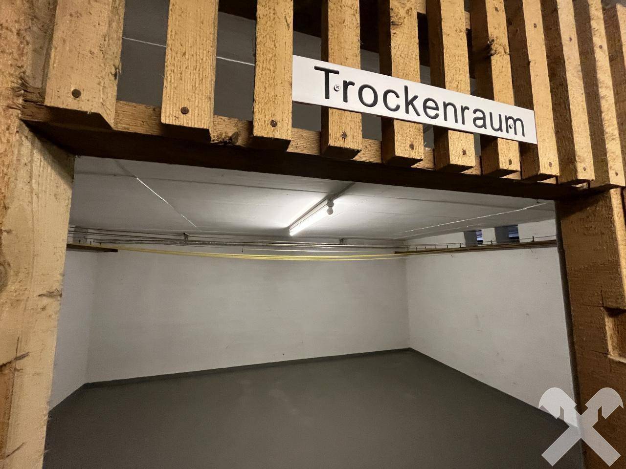 Trockenraum im Keller mit einfacher Beleuchtung und Betonboden.