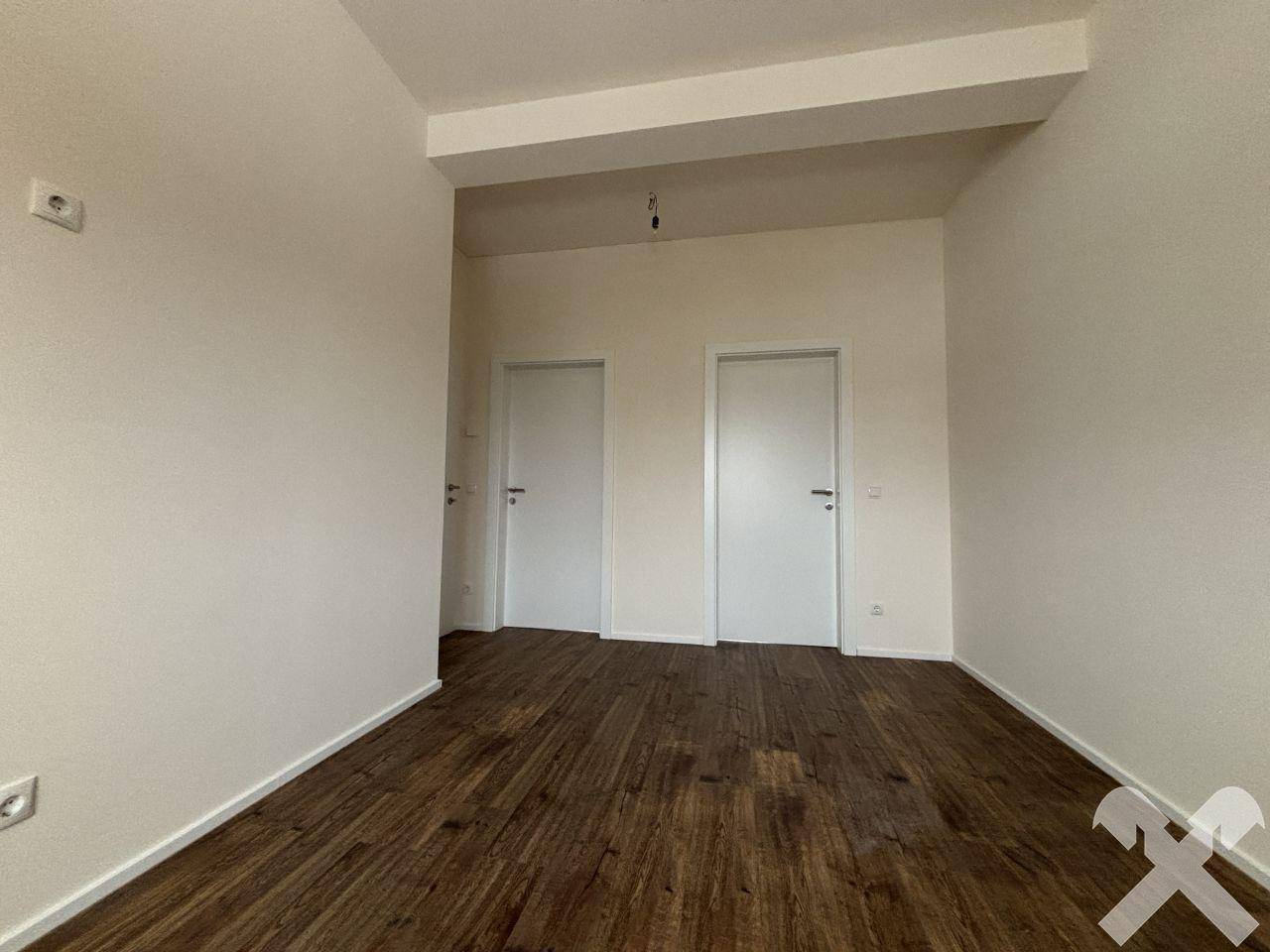Leerer Raum mit Laminatboden und zwei Türen, ideal für Schlaf- oder Arbeitszimmer.