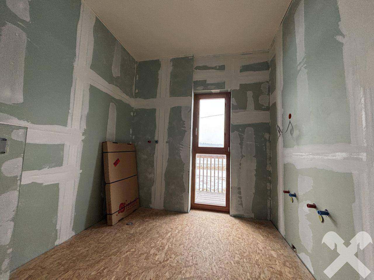 Raum im Rohbauzustand mit OSB-Boden und Fenster, bereit für den weiteren Ausbau.