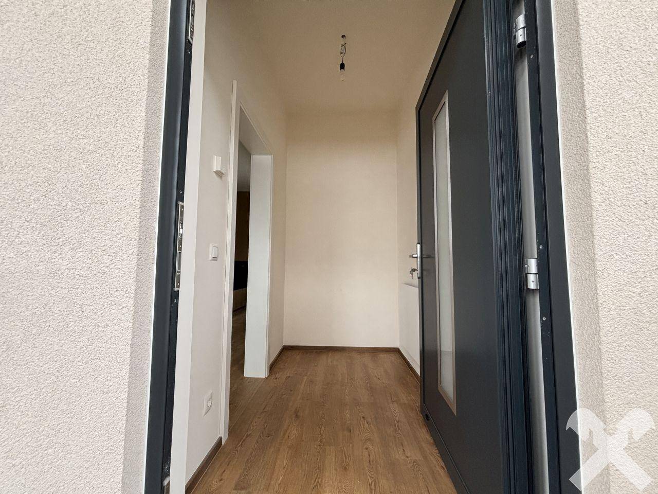 Heller Eingangsbereich mit moderner Haustür und Holzboden, der in den Wohnbereich führt.