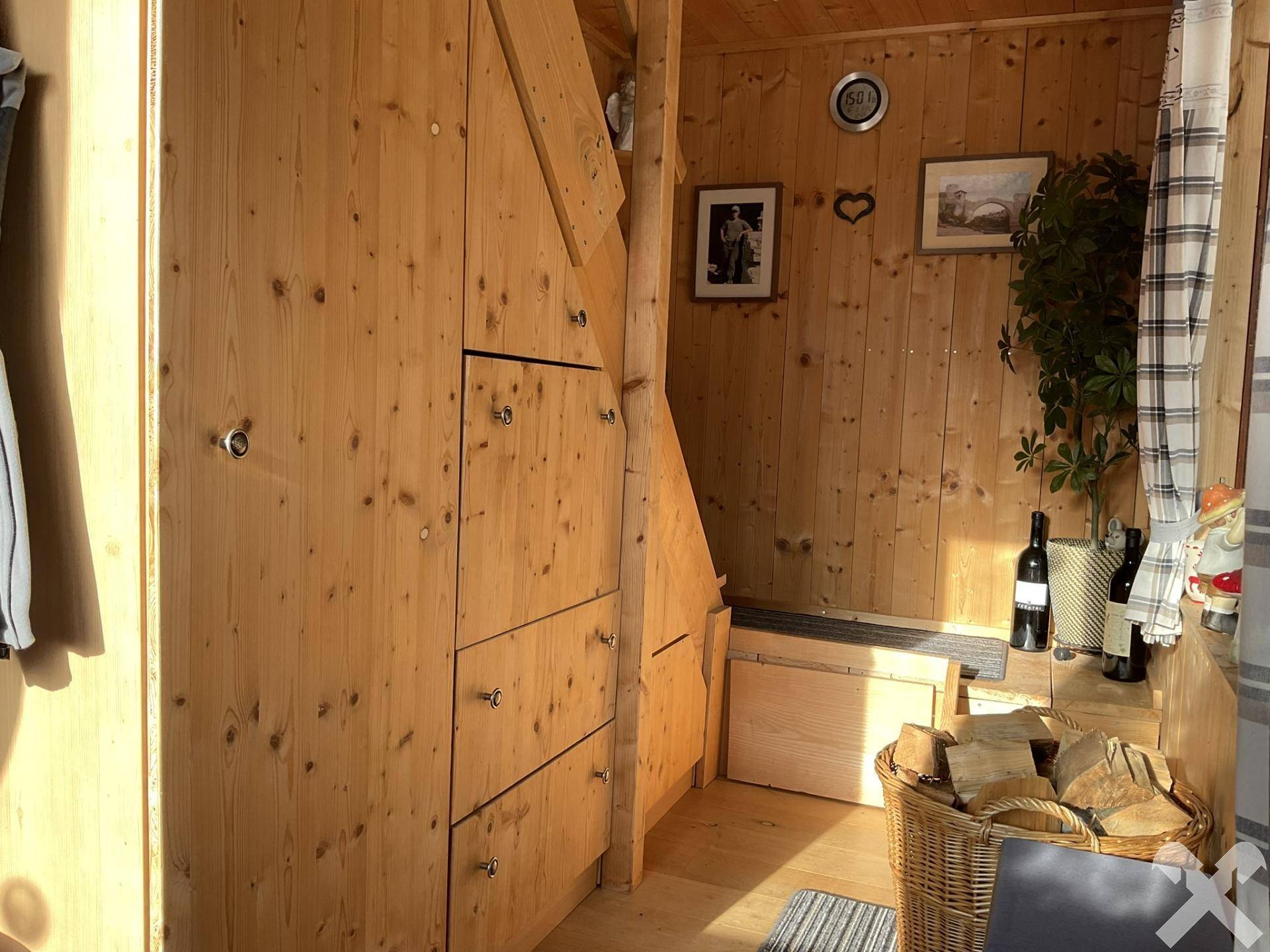 Rustikaler Flur mit Einbauschränken aus Holz und Kaminholzkorb, typisch für ein Chalet.