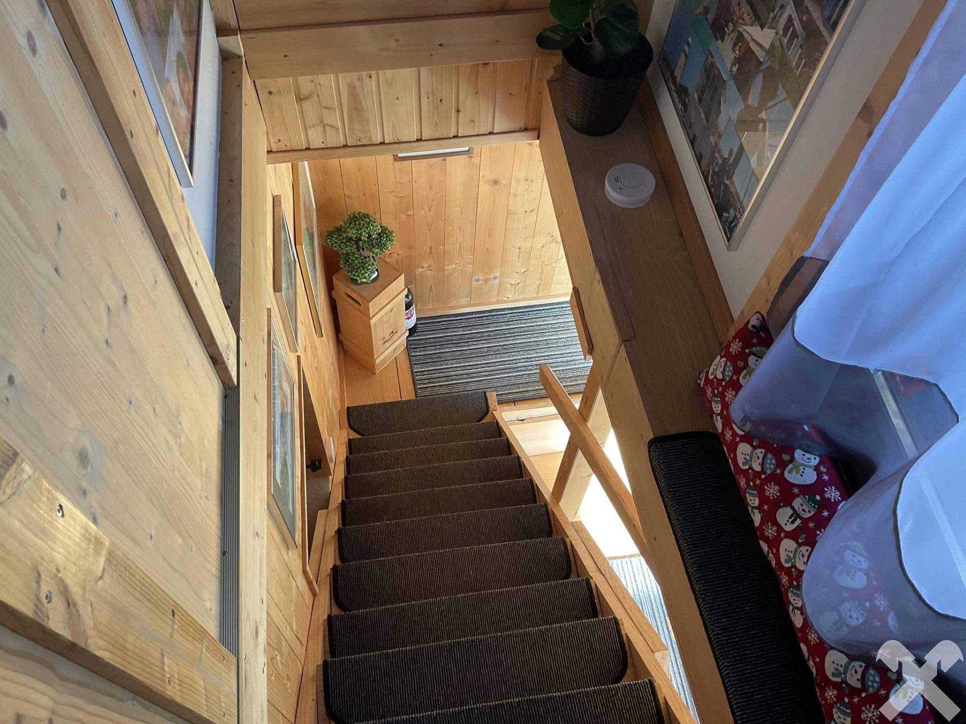 Holztreppe führt in den oberen Bereich, umgeben von rustikaler Holzvertäfelung.