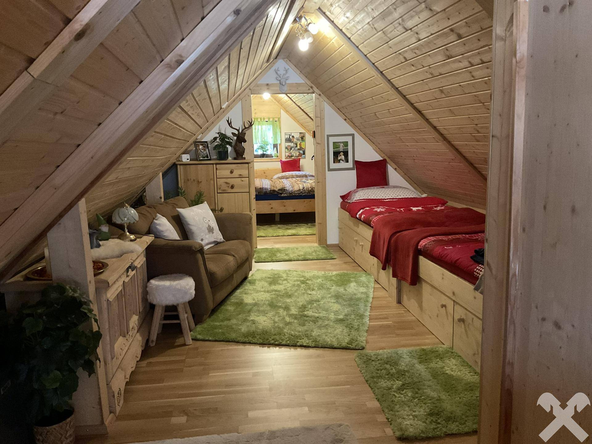 Gemütliches Schlafzimmer im Dachgeschoss mit Holzvertäfelung, schrägen Decken und mehreren Betten.