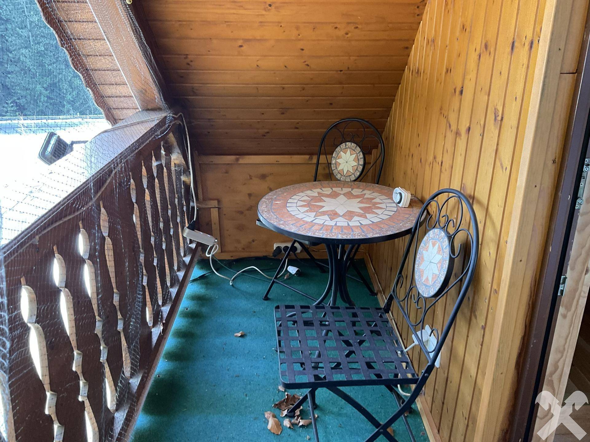 Kleiner Balkon mit schmiedeeisernen Möbeln und Holzvertäfelung, ideal für eine Pause.