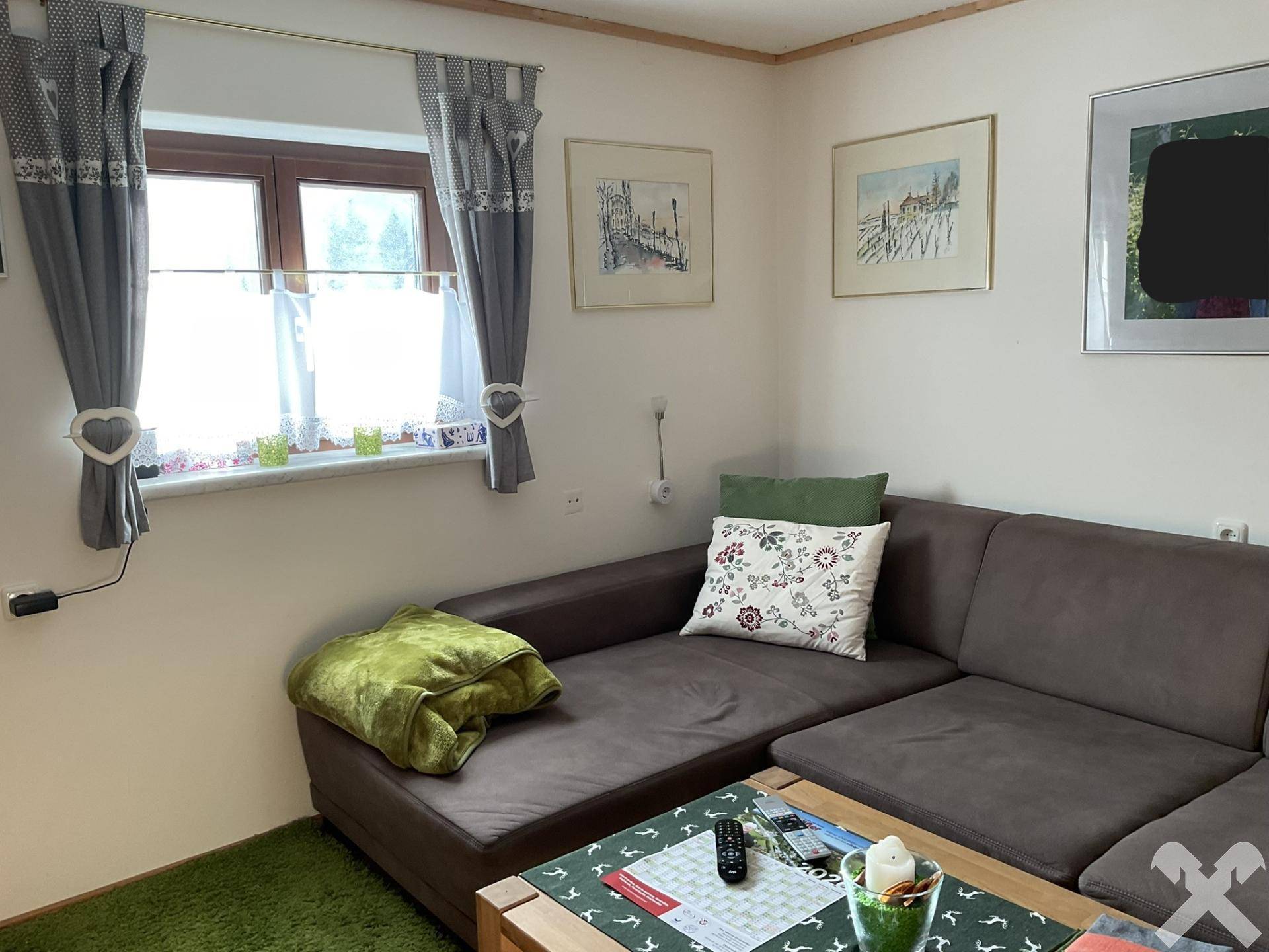 Heller Wohnbereich mit bequemer Couch, Fenster und traditionellen Vorhängen.