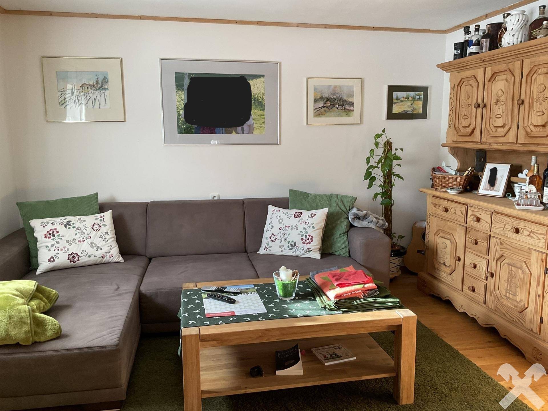 Gemütliches Wohnzimmer mit Ecksofa, Holztisch und traditionellen Schränken.