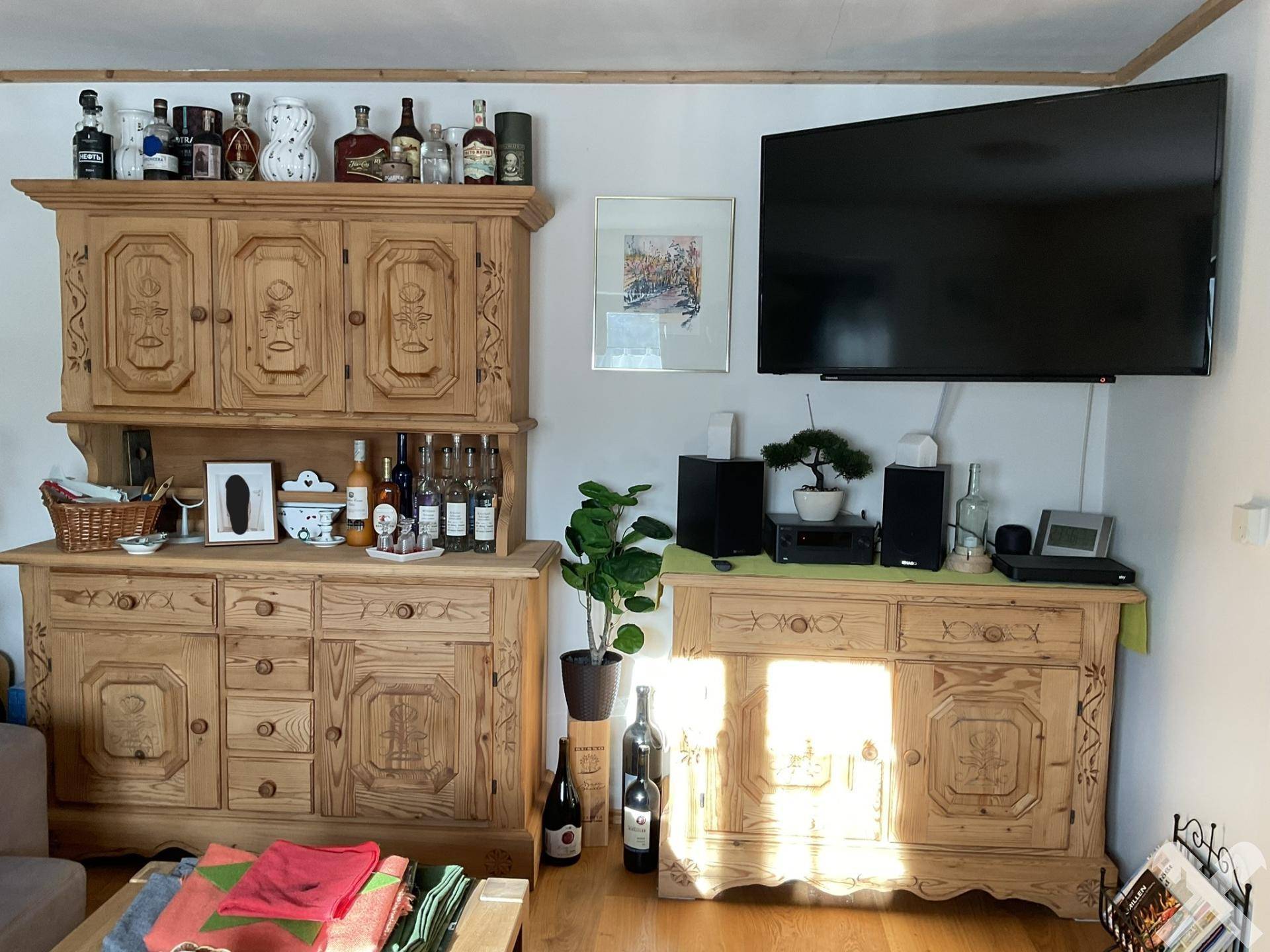 Wohnzimmer mit traditionellen Holzmöbeln, Fernseher und dekorativen Elementen.