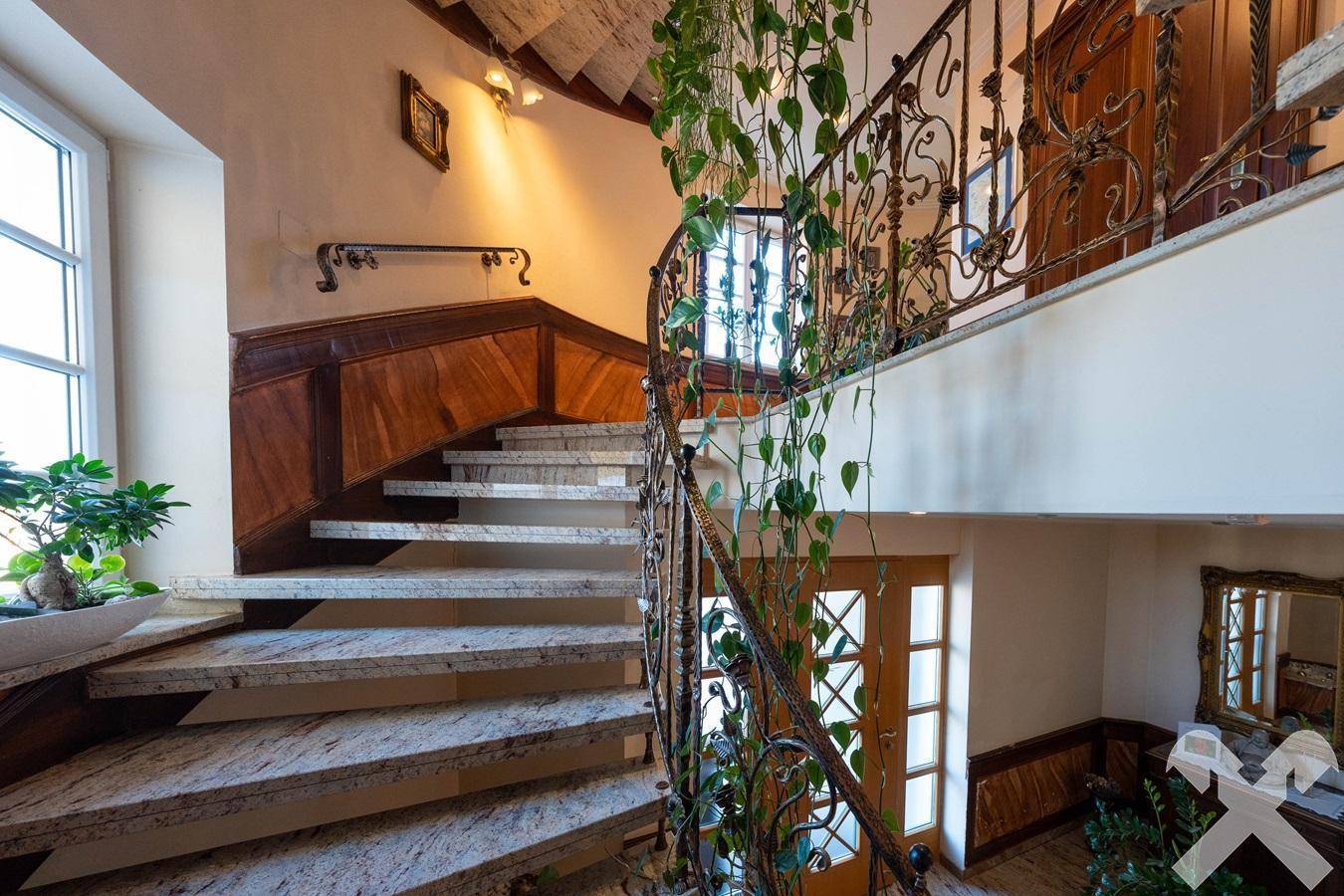 Elegante Marmortreppe mit schmiedeeisernem Geländer und Pflanzenverzierung.
