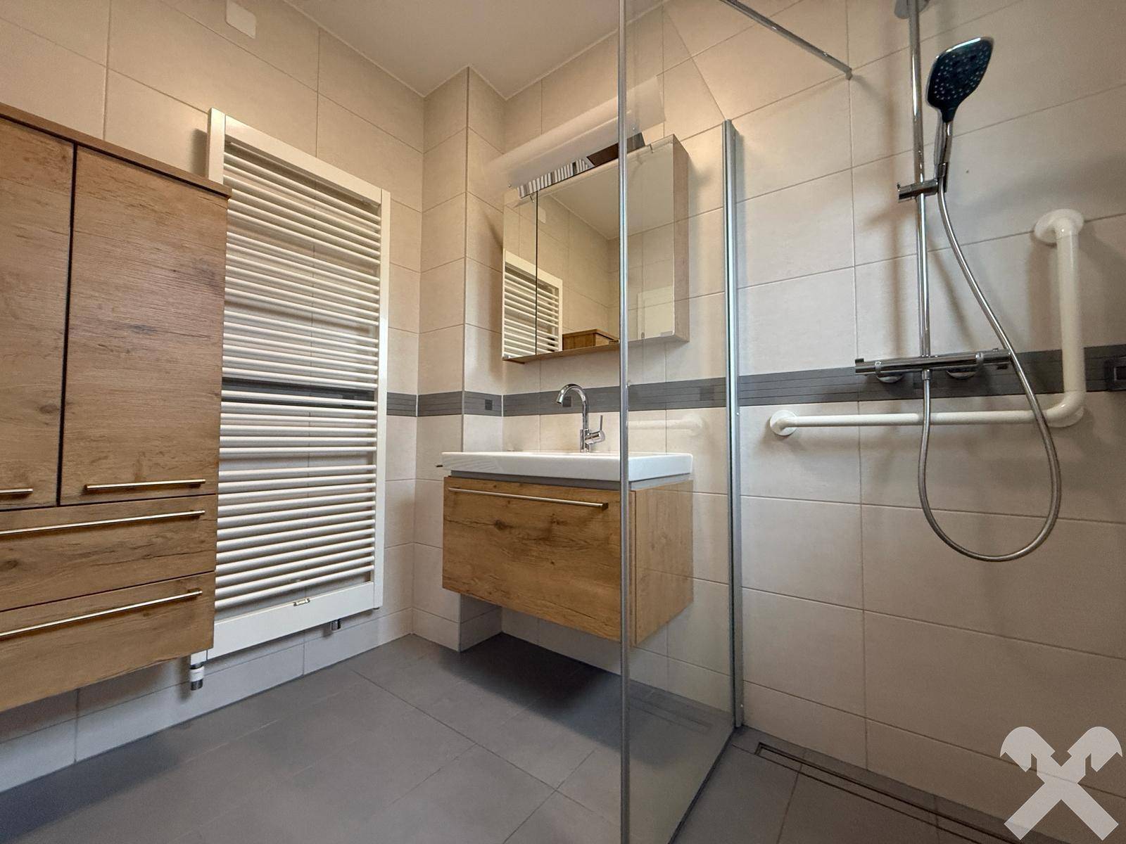 Modernes Badezimmer mit ebenerdiger Dusche, Holzwaschtisch und Handtuchheizkörper.