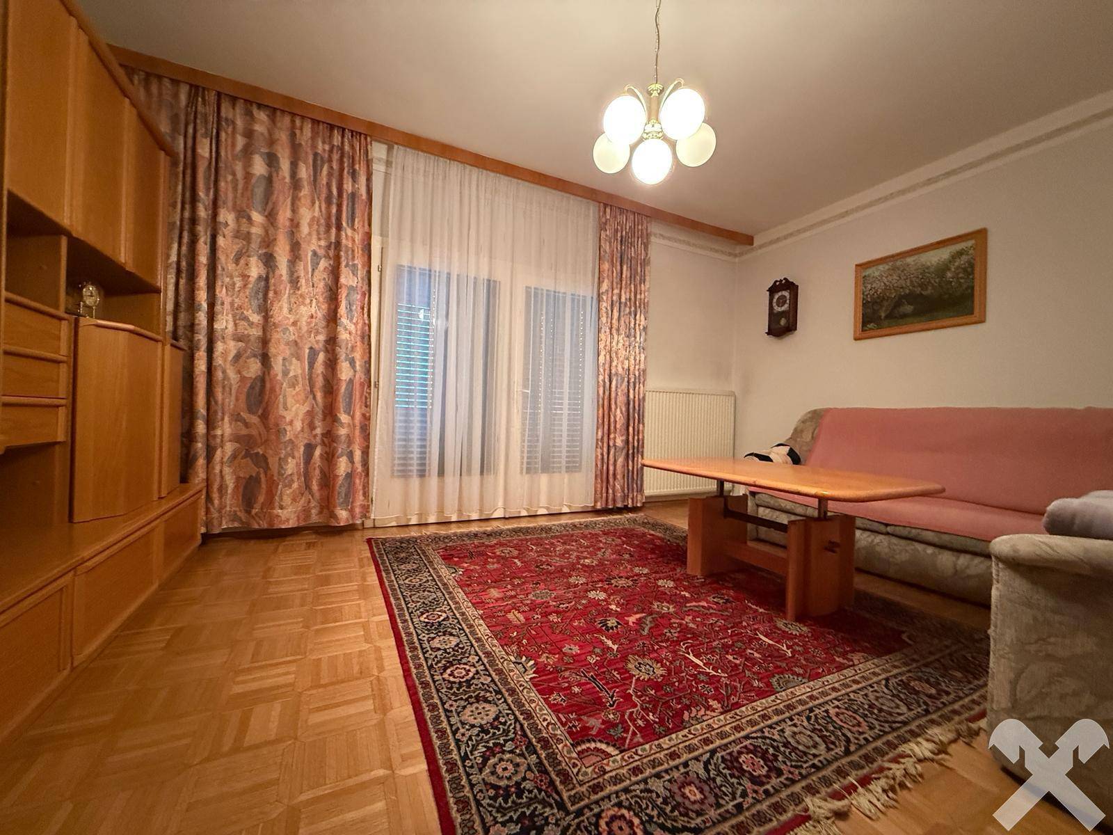 Wohnzimmer mit Parkettboden, großem Teppich und Holzmöbeln in traditionellem Stil.