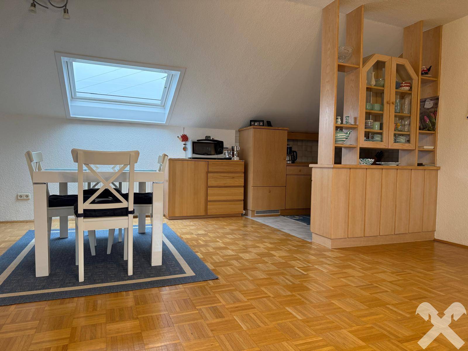 Heller Wohn-Essbereich im Dachgeschoss mit Holzboden, Esstisch und Dachfenster.