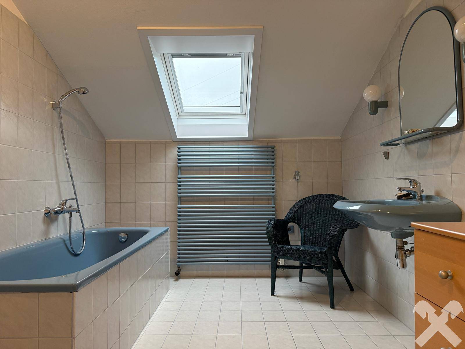 Badezimmer im Dachgeschoss mit Badewanne, Waschbecken und Dachfenster.