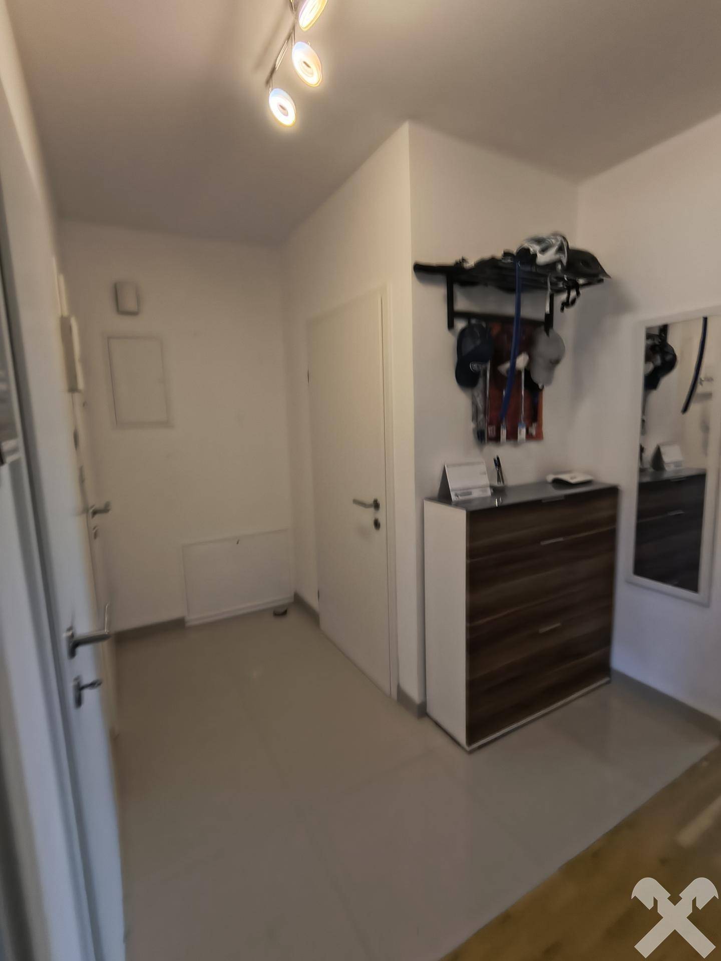 Heller Eingangsbereich mit Fliesenboden, Schuhschrank und Garderobe an der Wand.