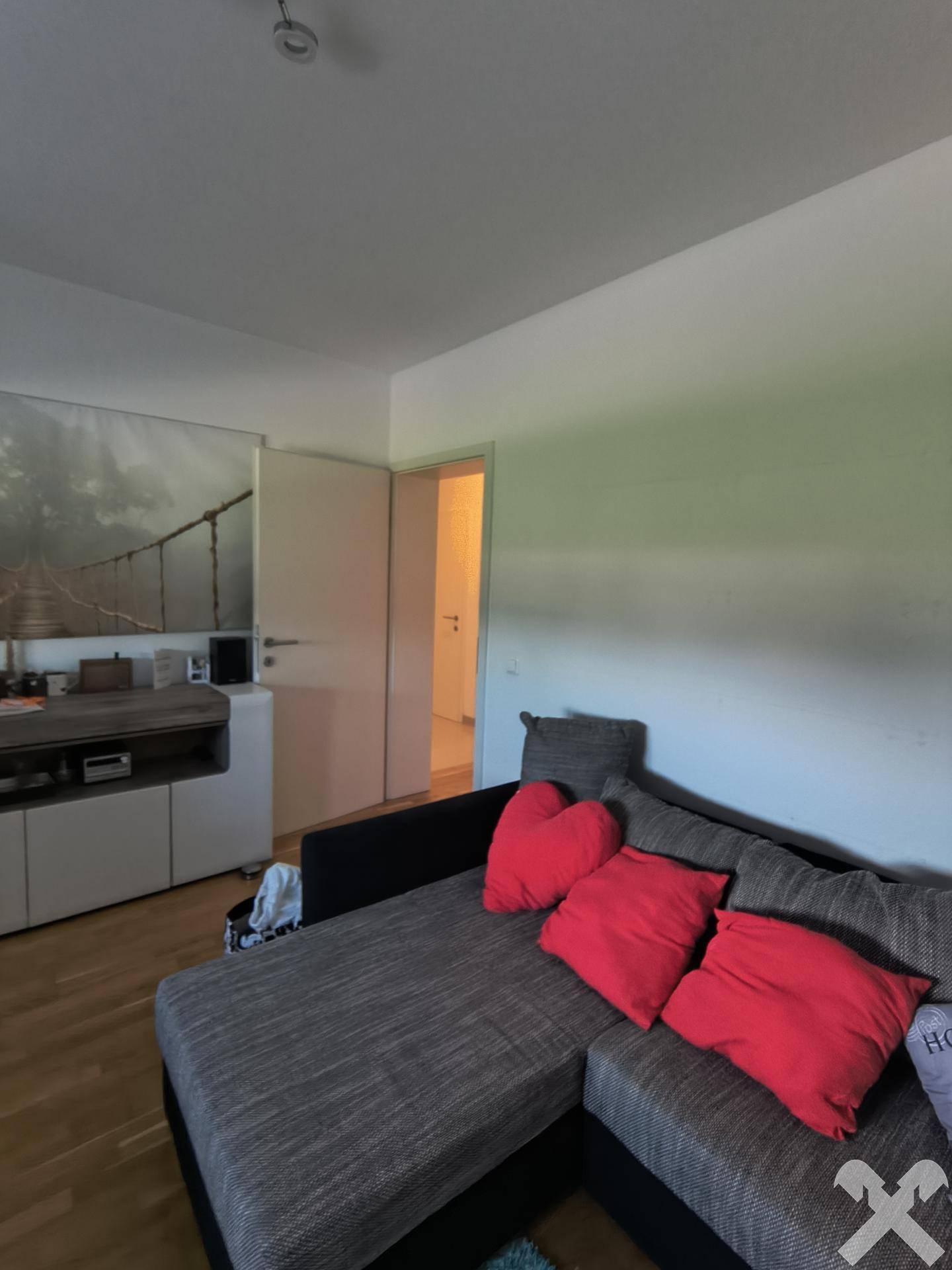 Gemütliches Wohnzimmer mit großem Ecksofa, Holzboden und moderner Wanddekoration.