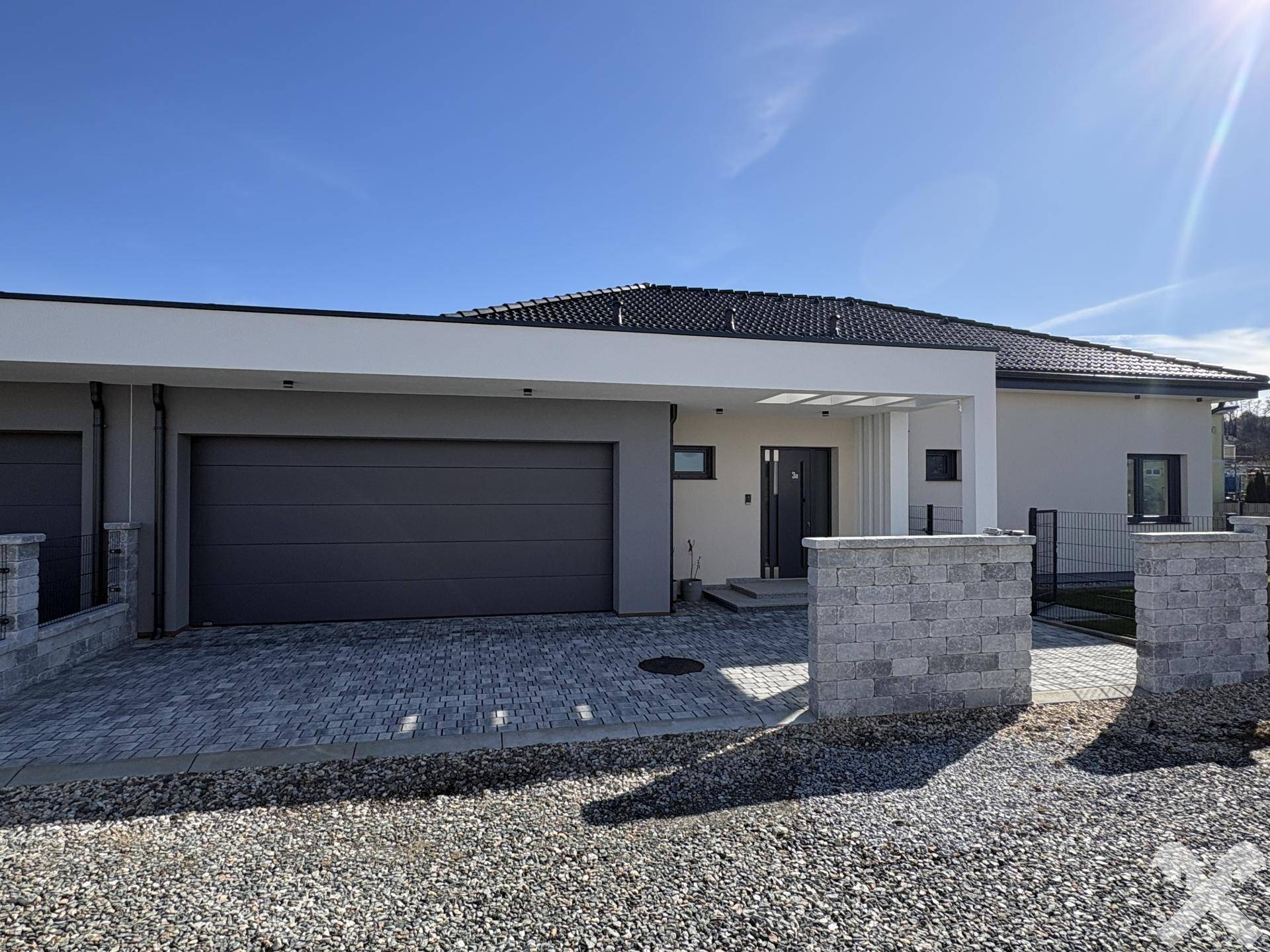 Vorderansicht des modernen Einfamilienhauses mit integrierter Garage und gepflegtem Eingangsbereich.