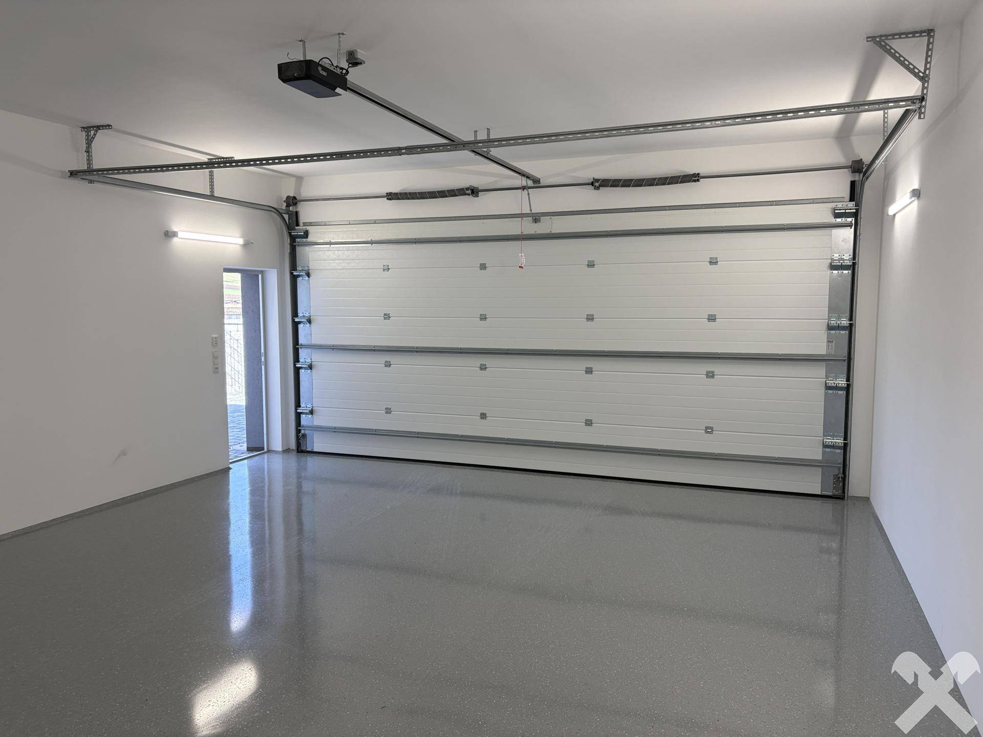 Geräumige und helle Garage mit automatischem Tor und glänzendem Boden.