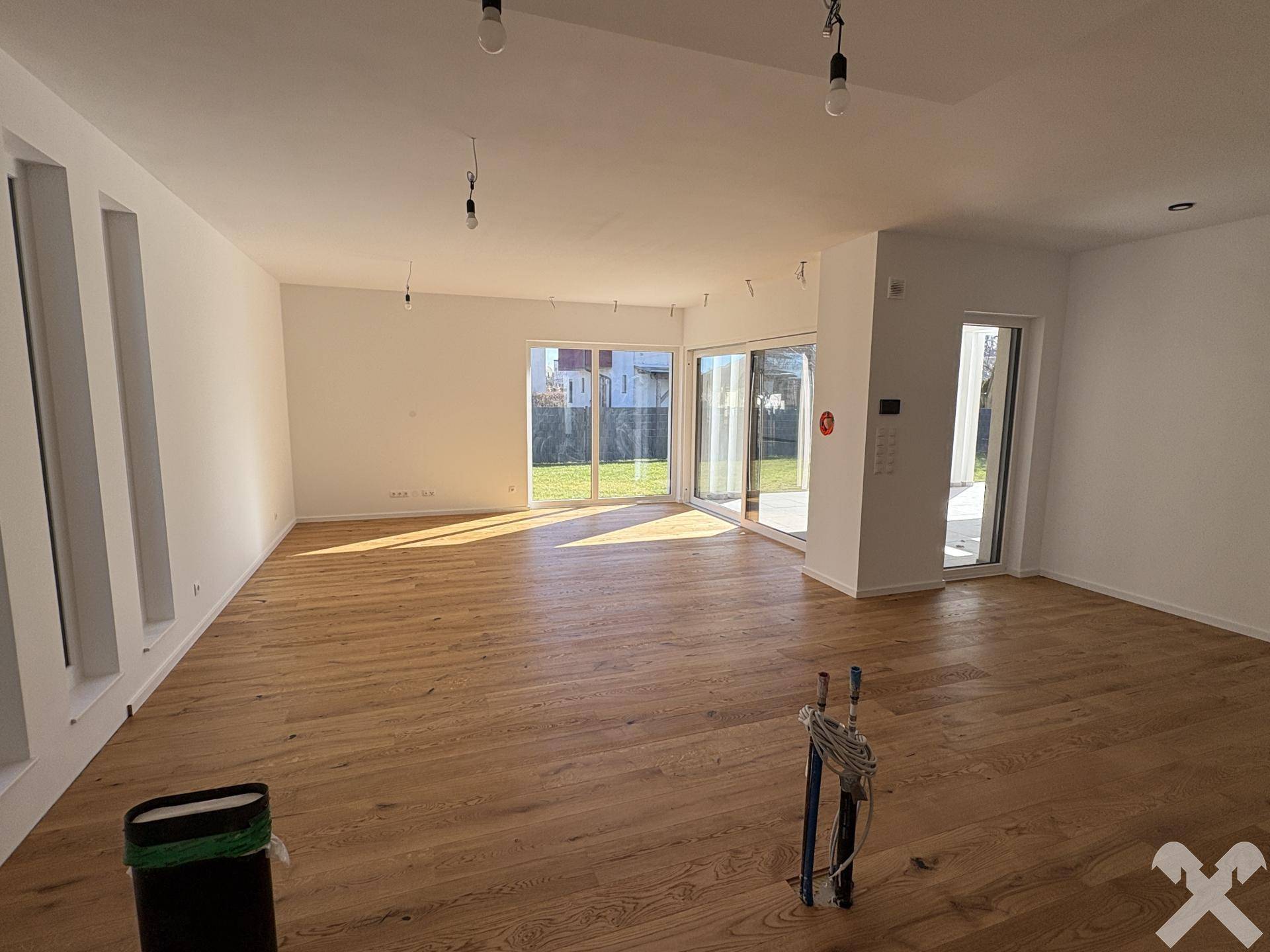 Weitläufiger Wohnbereich mit Holzboden und großen Schiebetüren, die den Zugang zum Außenbereich ermöglichen.
