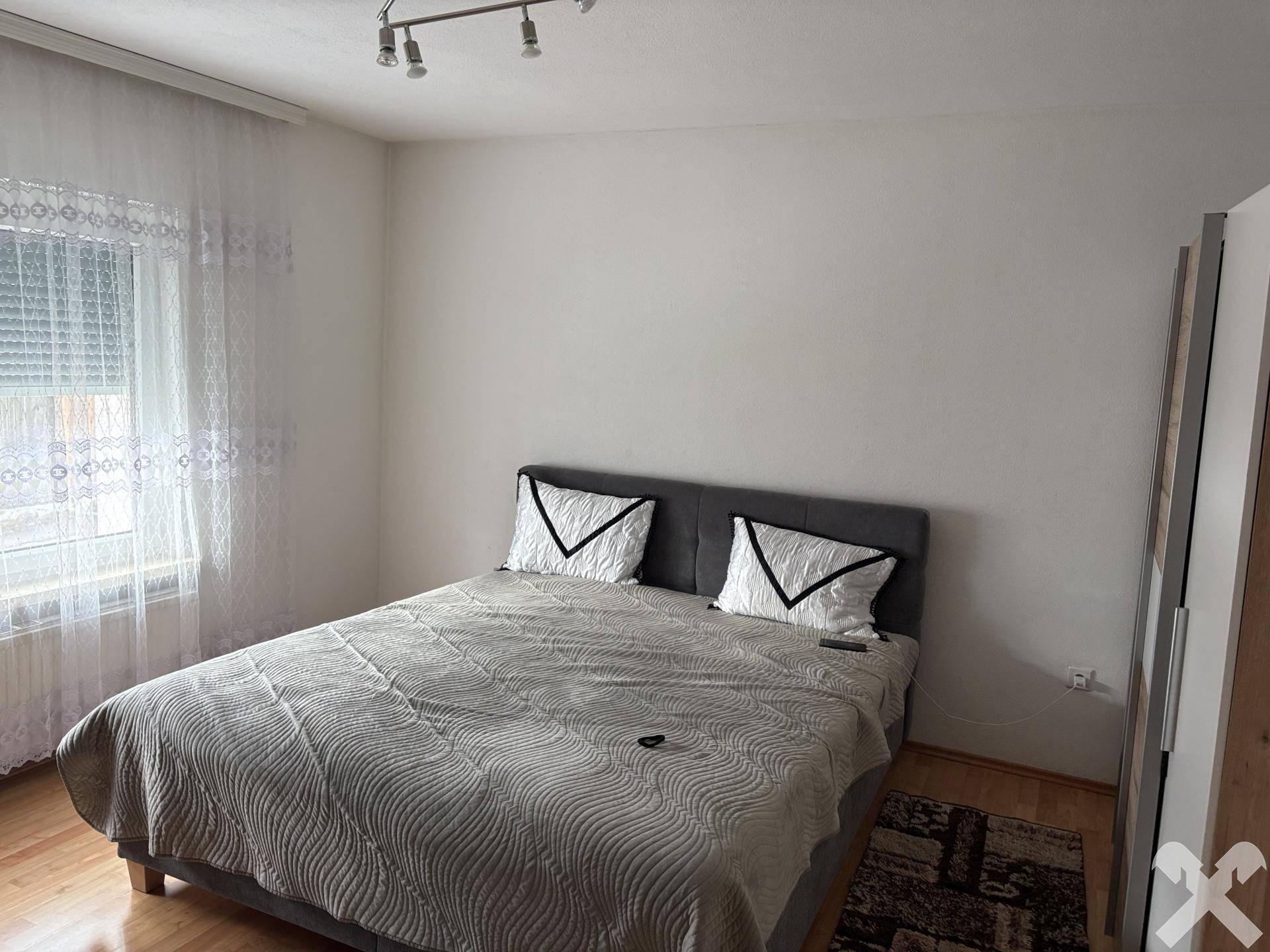 Schlafzimmer mit Doppelbett, Holzfußboden und Fenster mit Rollladen für Privatsphäre.